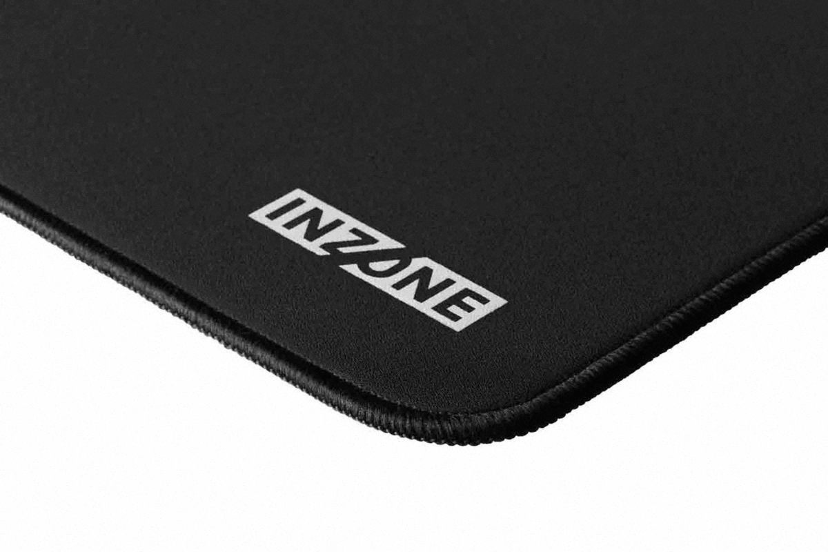 Zbliżenie czarnej podkładki pod mysz z białym logo 'INZONE'. Krawędzie mają szytą obwódkę.