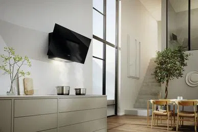 Siyah davlumbazlı, dolaplı ve pencereli modern bir mutfak. Arka planda bir ağaç ve masa görülebilir.