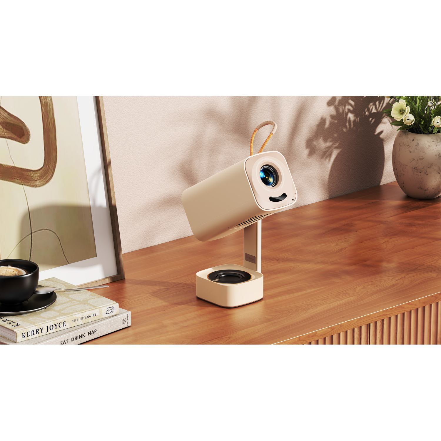A beige projector on a stand is on a wooden table. Books, a coffee cup, and a flower vase are also on the table.