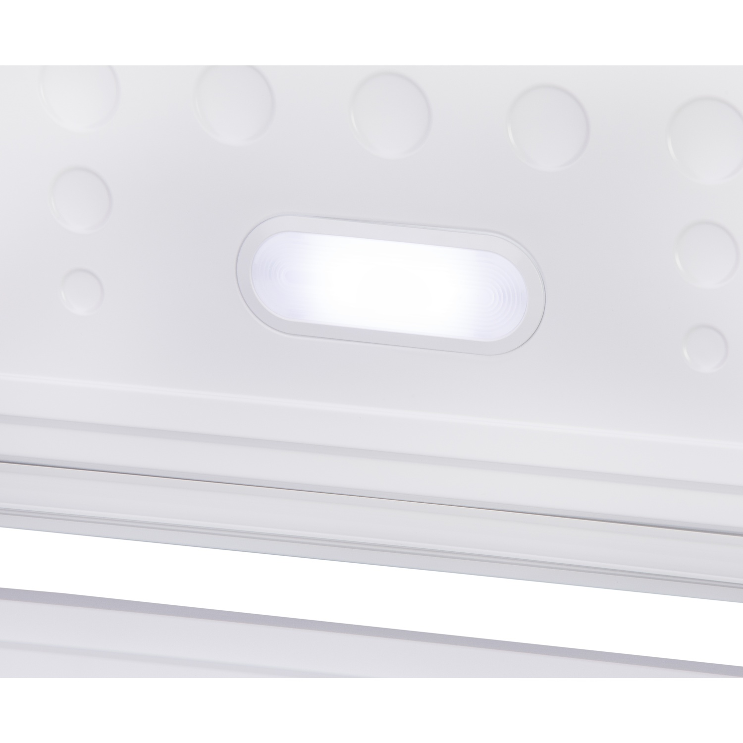 Intérieur d'un réfrigérateur. Intérieur blanc avec un luminaire rectangulaire brillant. Plusieurs renfoncements ronds sont visibles sur la surface.