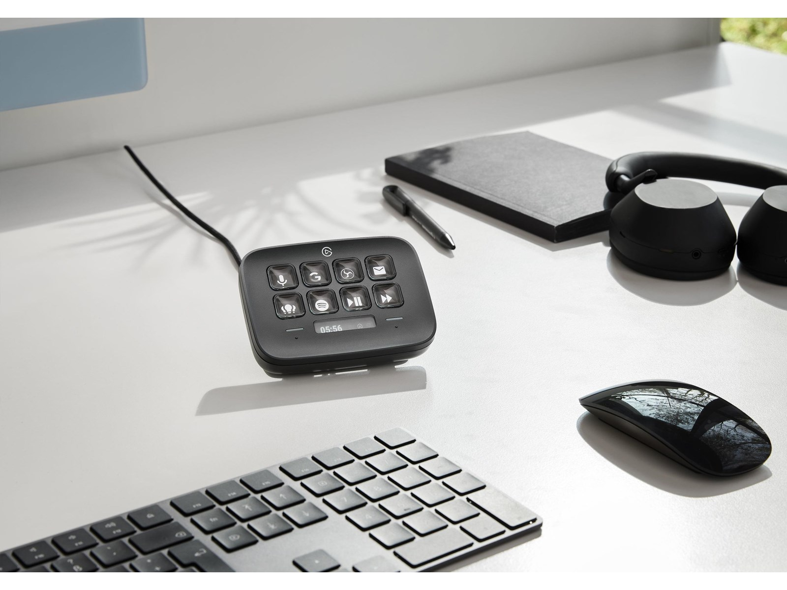 Una configuración de escritorio incluye teclado, ratón, auriculares y un panel de control. El panel muestra iconos y una pantalla. El fondo es blanco.