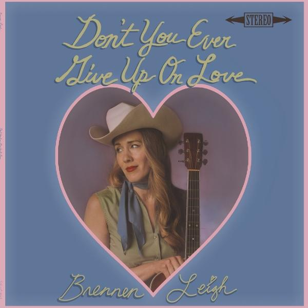 Albumcover mit Frau in Cowboyhut, die eine Gitarre in Herzform hält. Der Text lautet 'Don't You Ever Give Up On Love' von Brennen Leigh.
