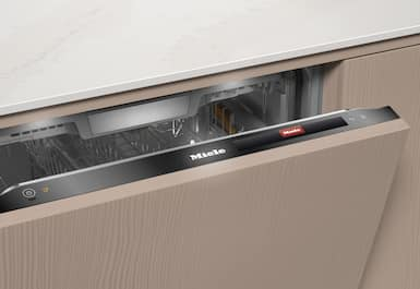 Kısmen açık bir Miele bulaşık makinesi. Kapı, marka adını gösteren siyah bir kulpla bej renktedir. İç kısım görülebilir.