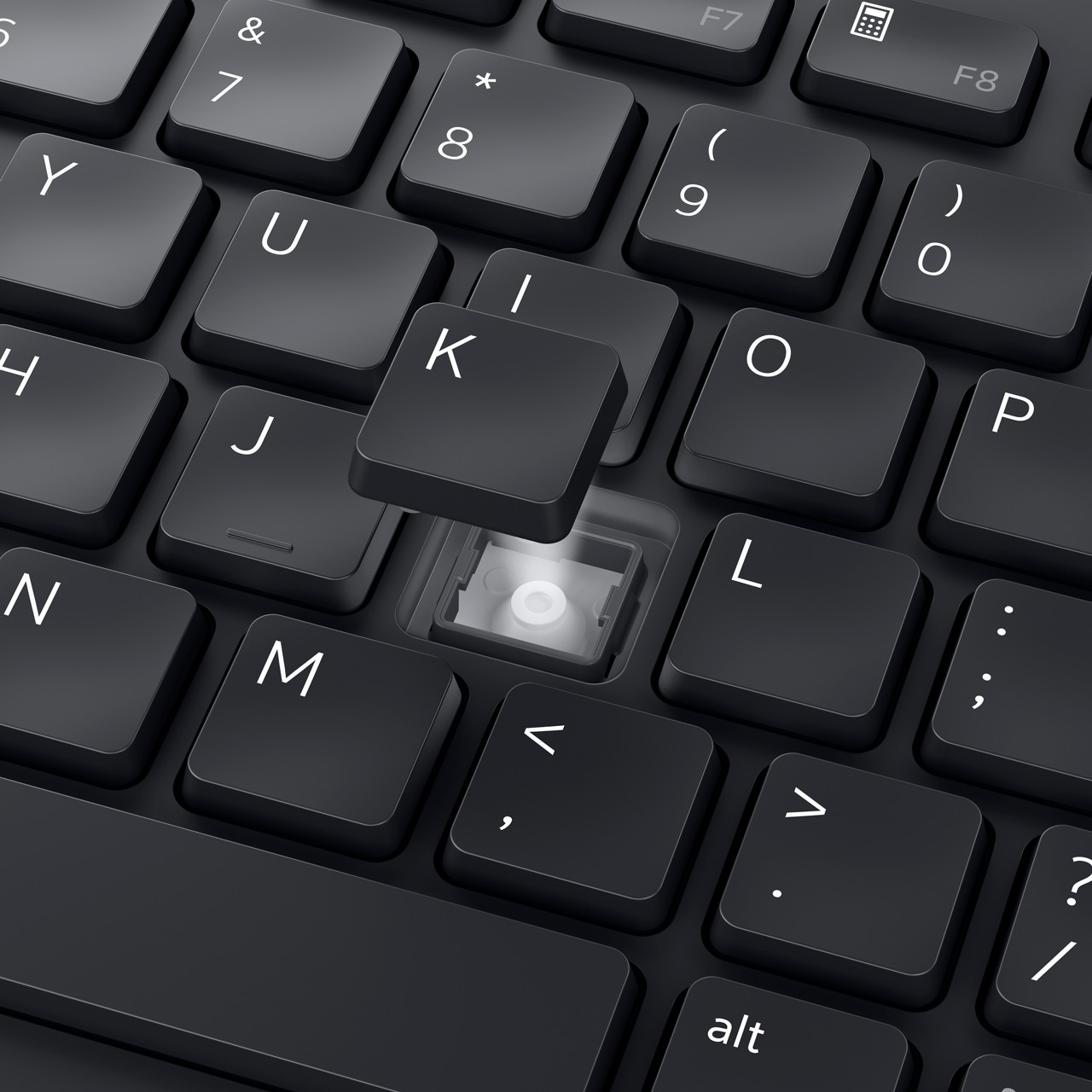 Nahaufnahme einer schwarzen Tastatur. Die K-Taste ist angehoben und gibt den Mechanismus darunter frei. Andere Tasten enthalten Buchstaben und Symbole.
