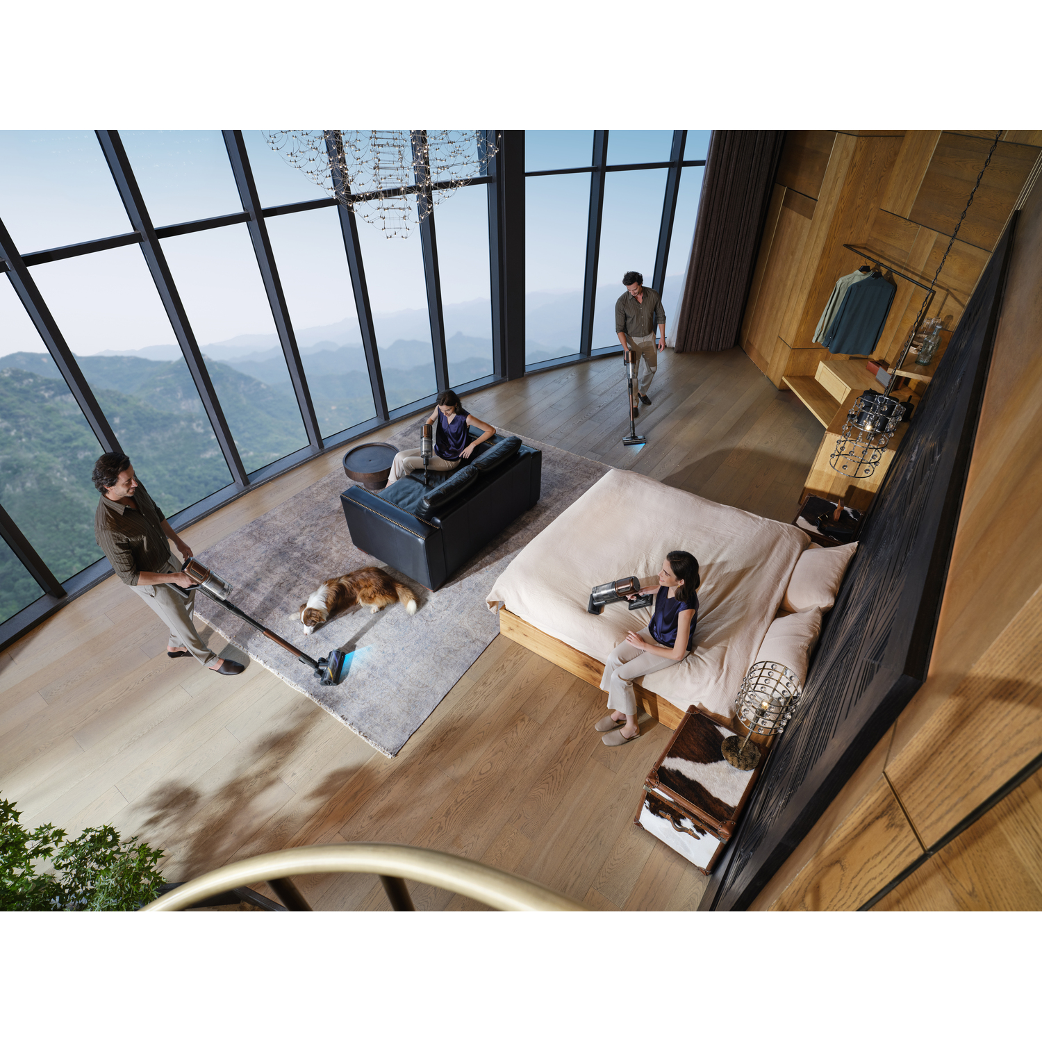 Four people vacuum a modern home with a large window view. A dog rests on a rug. Mountains are visible outside.