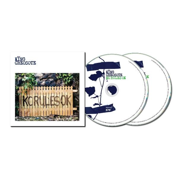 Albumcover und zwei CDs. Das Cover zeigt einen Holzzaun mit der Aufschrift 'KORULES OK'. CDs haben blaues Blumendesign und Text.