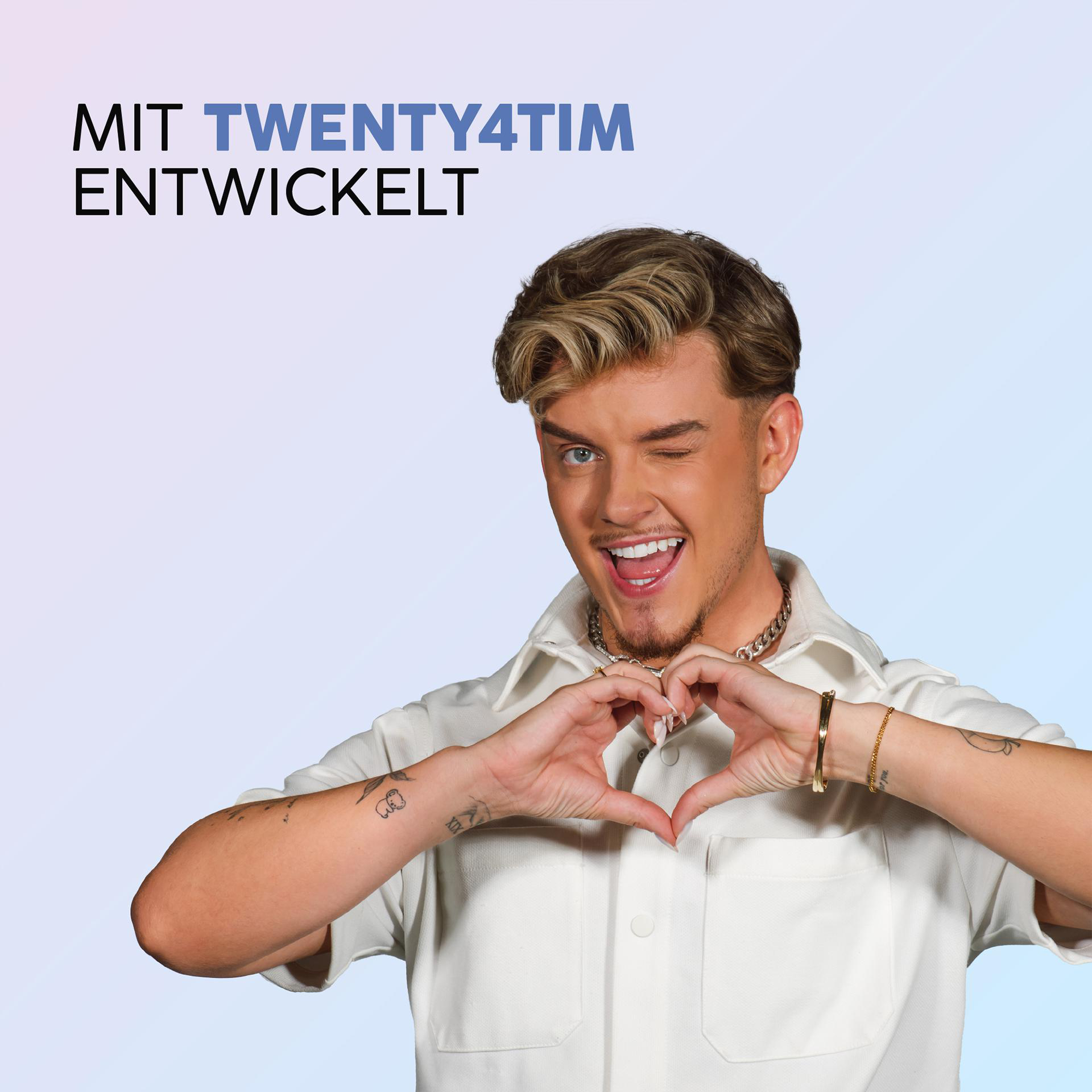 Ein Mann zwinkert, formt mit seinen Händen ein Herz und lächelt. Er trägt ein weißes Hemd und Schmuck. Text: 'MIT TWENTY4TIM...