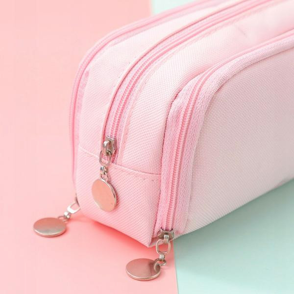 Różowy piórnik z dwoma zamkami błyskawicznymi. Zamki są różowe. Tło podzielone na różowy i jasny zielony.