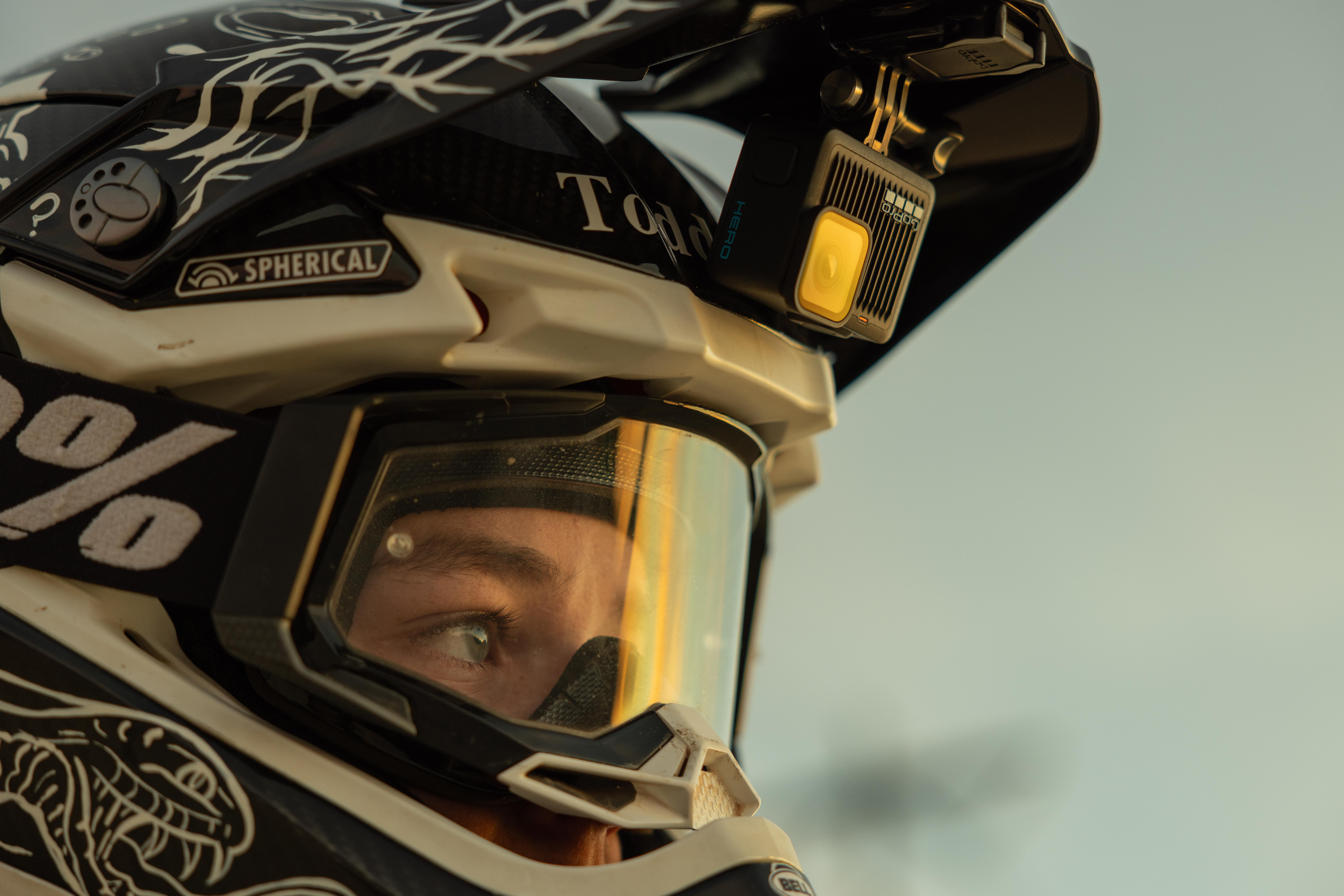 Nahaufnahme einer Person mit Motorradhelm, Brille und GoPro-Kamera. Der Hintergrund ist unscharf.
