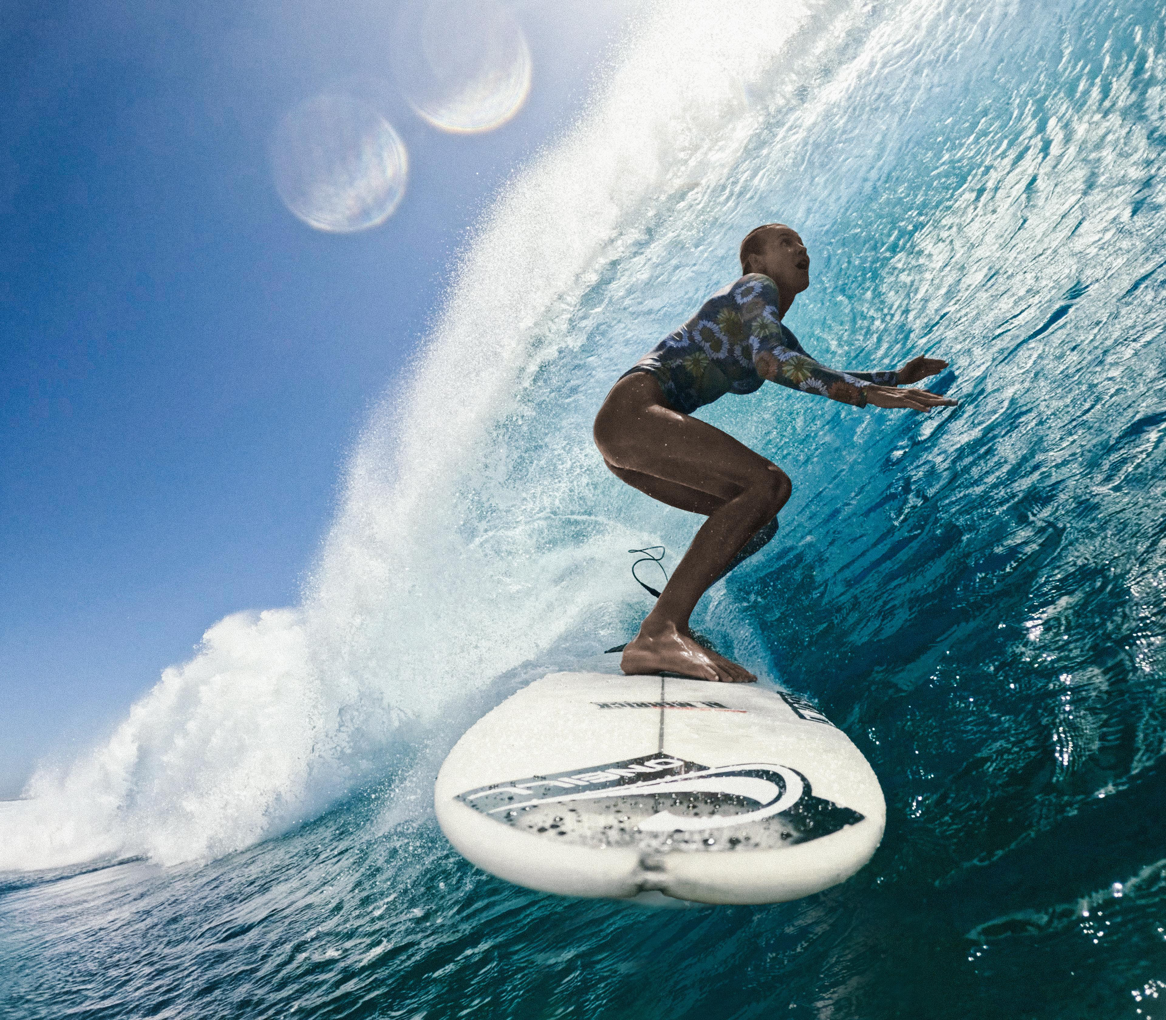 Ein Surfer reitet eine Welle. Der Surfer steht auf einem weißen Surfbrett. Der Himmel ist blau. Die Welle ist tiefblau.