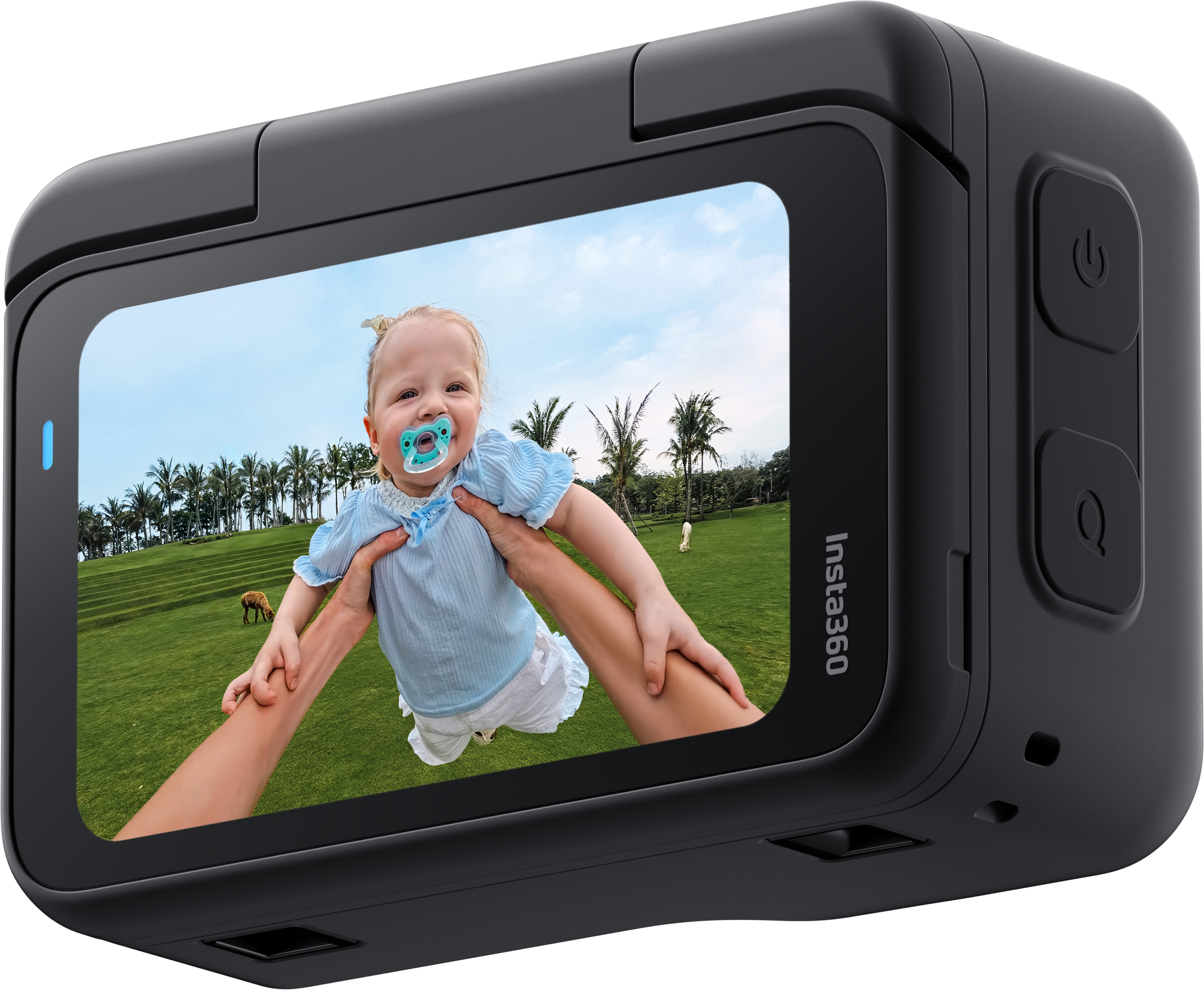 Ein Baby wird hochgehalten, lächelt, trägt ein blaues Hemd, vor einem grünen Feld und Palmen. Insta360 Kamera im Bild.