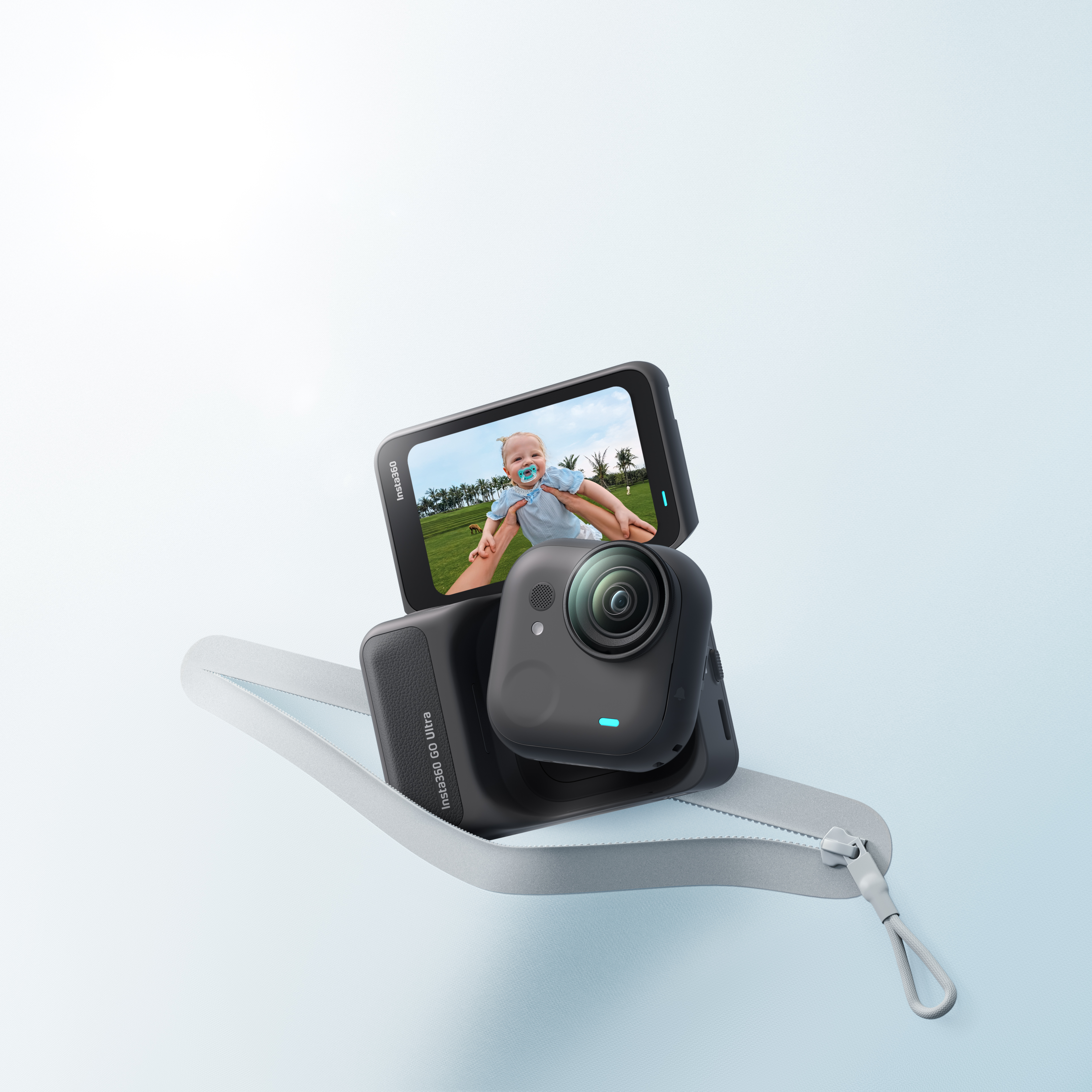 Schwarze Insta360-Kamera mit Display, das ein Baby zeigt. Kamera in einem Gehäuse mit Reißverschluss. Hellblauer Hintergrund.
