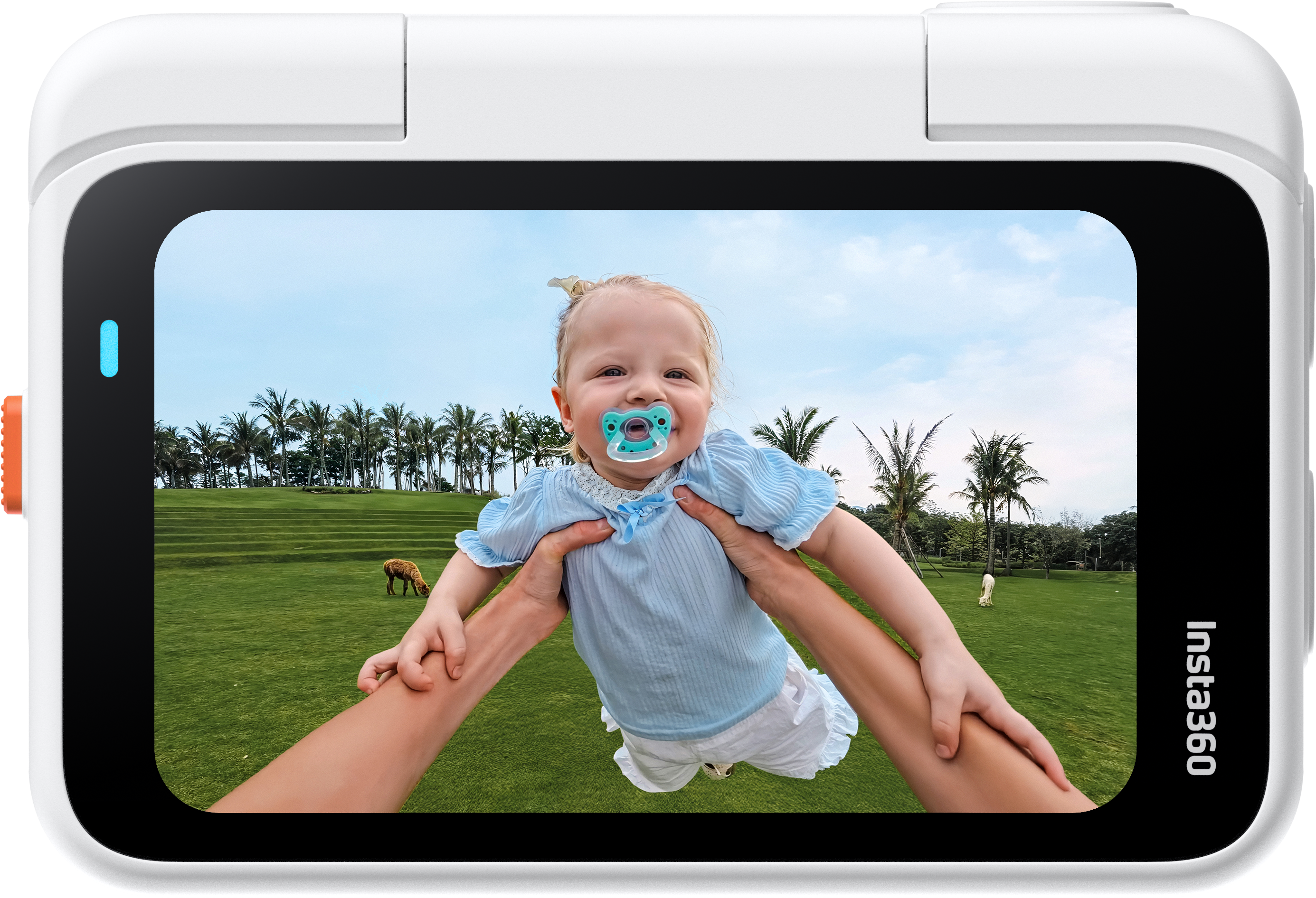 Ein Baby lächelt, während es hochgehalten wird und einen Schnuller trägt. Palmen und ein grasbewachsener Hügel sind im Hintergrund.