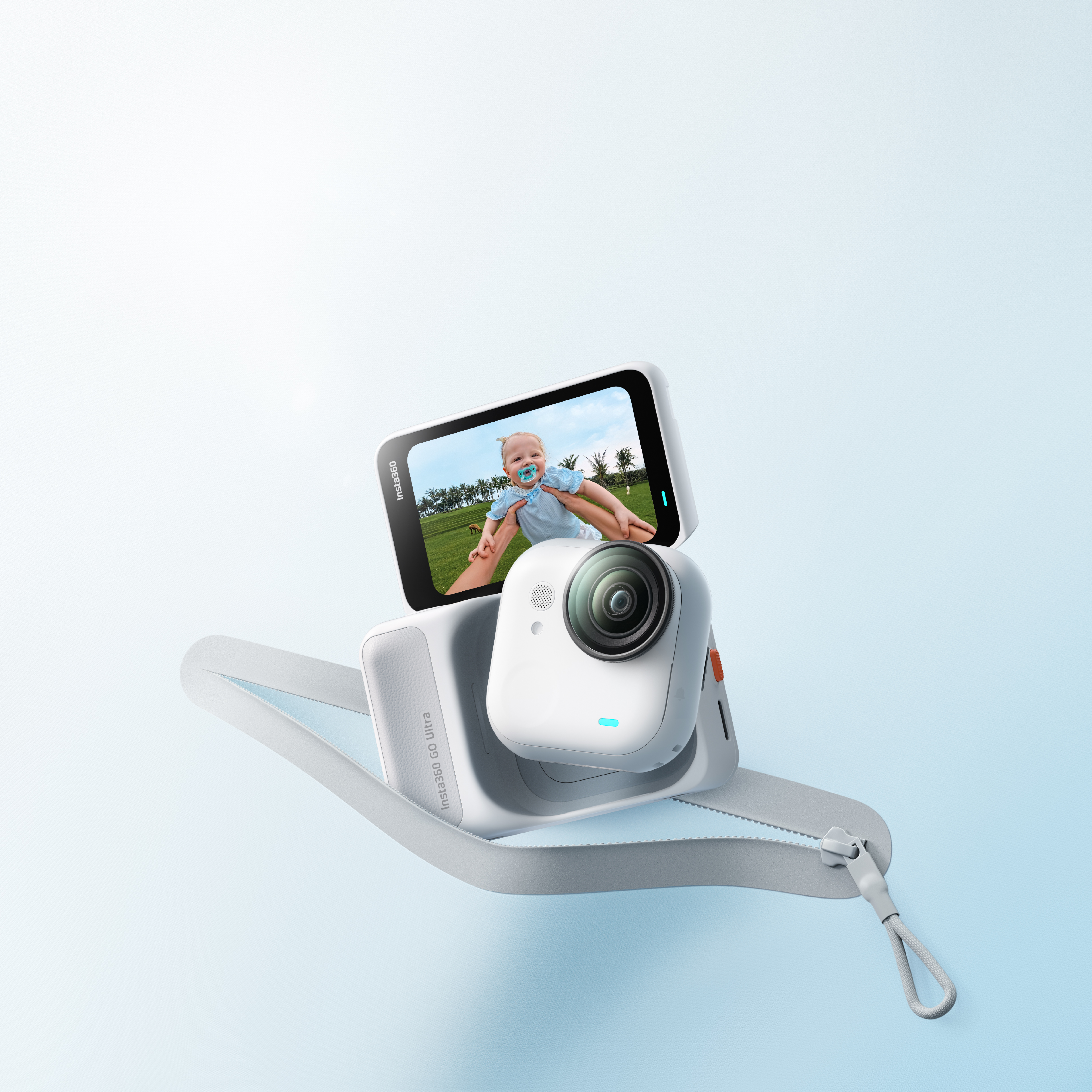 Eine weiße Insta360 Go Ultra Kamera zeigt ein Baby auf dem Bildschirm. Sie ist an einem grauen Gurt befestigt. Hellblauer Hintergrund.