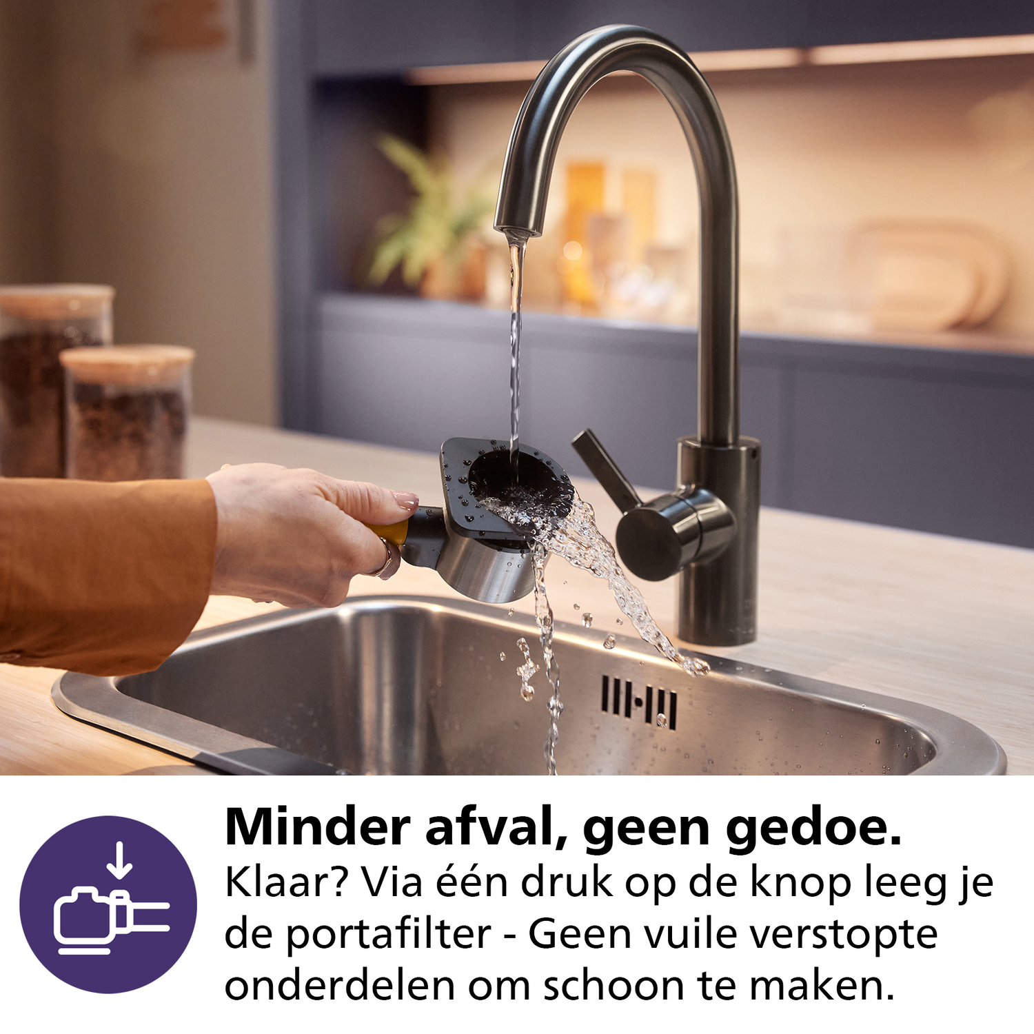 Een persoon spoelt een koffie portafilter af onder een keukenkraan. Water stroomt in de portafilter, over een roestvrijstalen spoelbak.