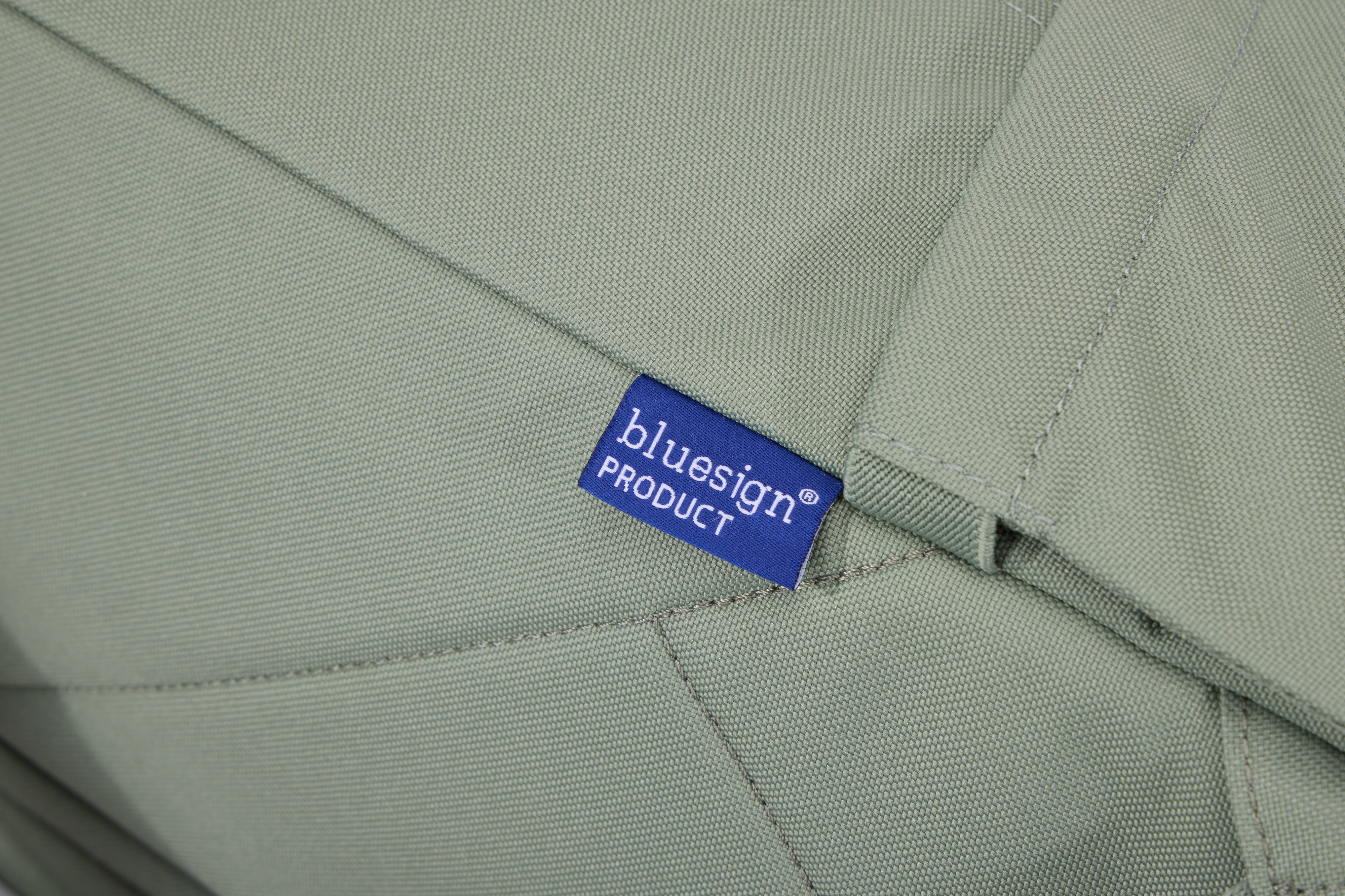 'bluesign PRODUCT' yazan mavi bir etiketle yeşil bir kumaşın yakından görünümü.