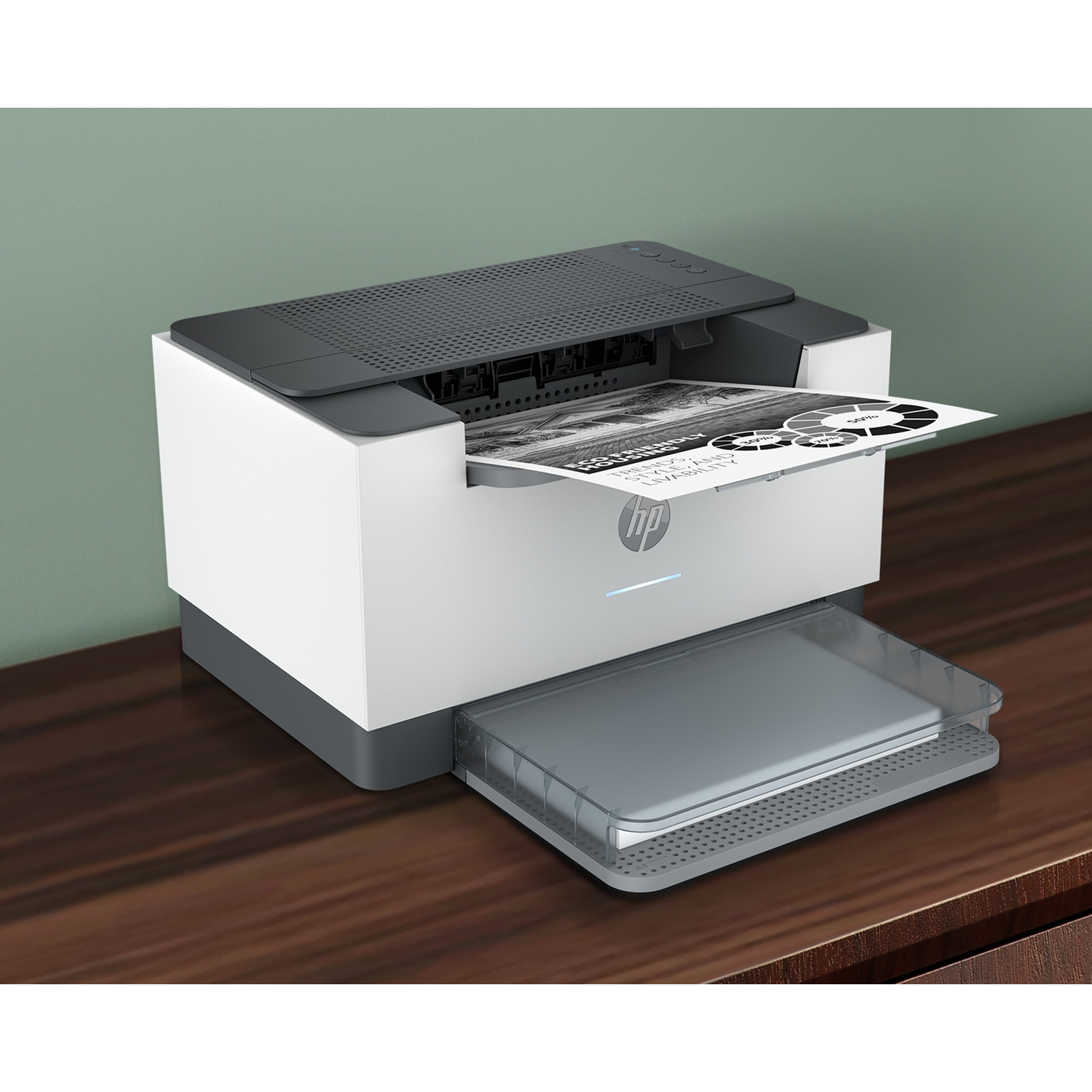 A white and gray HP printer on a wooden table is printing a document with a circular diagram. Green wall in background.