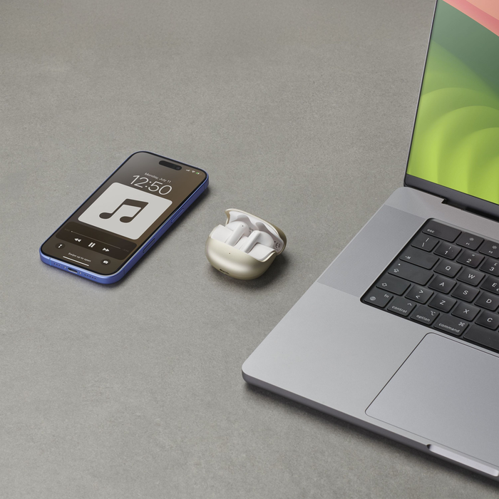Ein Telefon, Ohrhörer und ein Laptop sind auf einer grauen Oberfläche angeordnet. Das Telefon zeigt eine Musik-App an. Der Laptop ist offen.