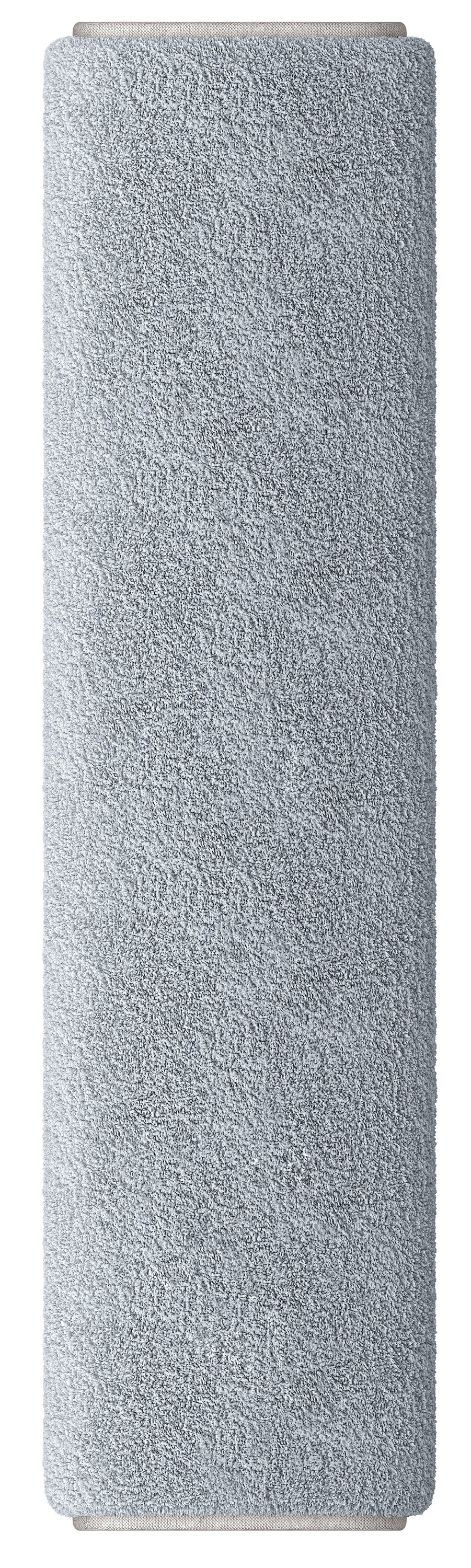 Zwinięty jasnoniebieski dywan z puszystą fakturą. Końce są w jasnobeżowym kolorze. Wyizolowany na białym tle.