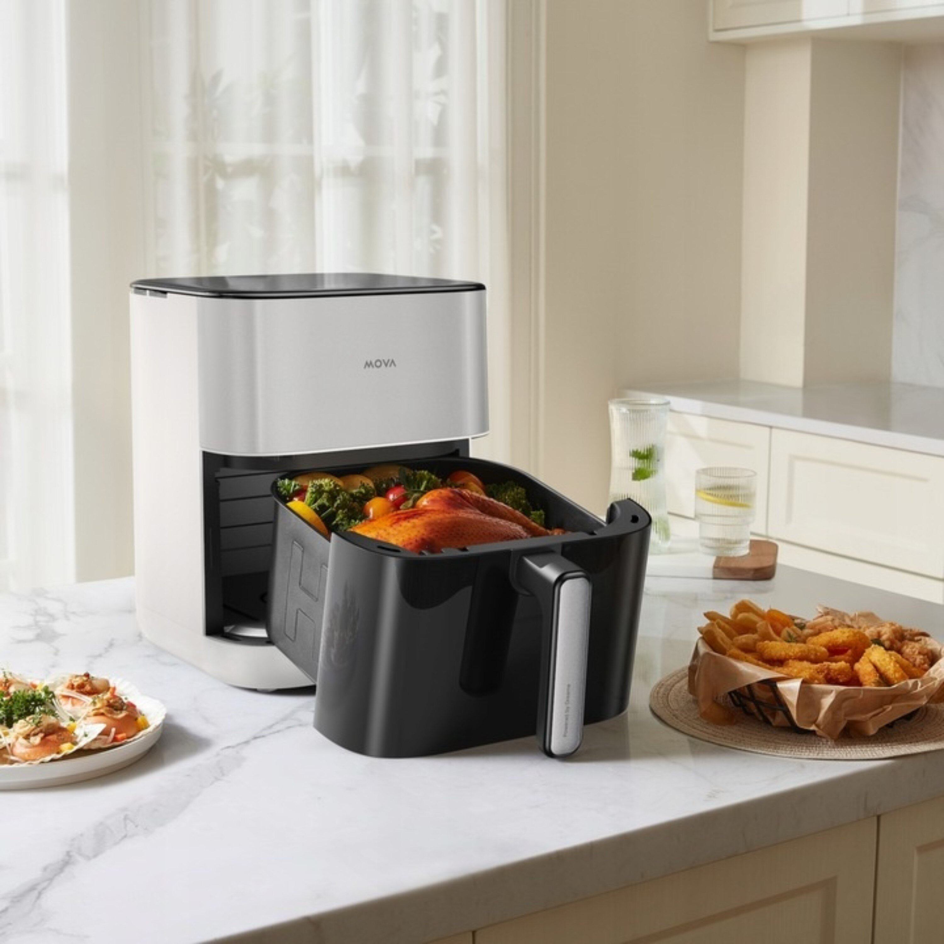 Frytkownica powietrzna z pieczonym kurczakiem w koszu. Inne produkty spożywcze są na marmurowym blacie.