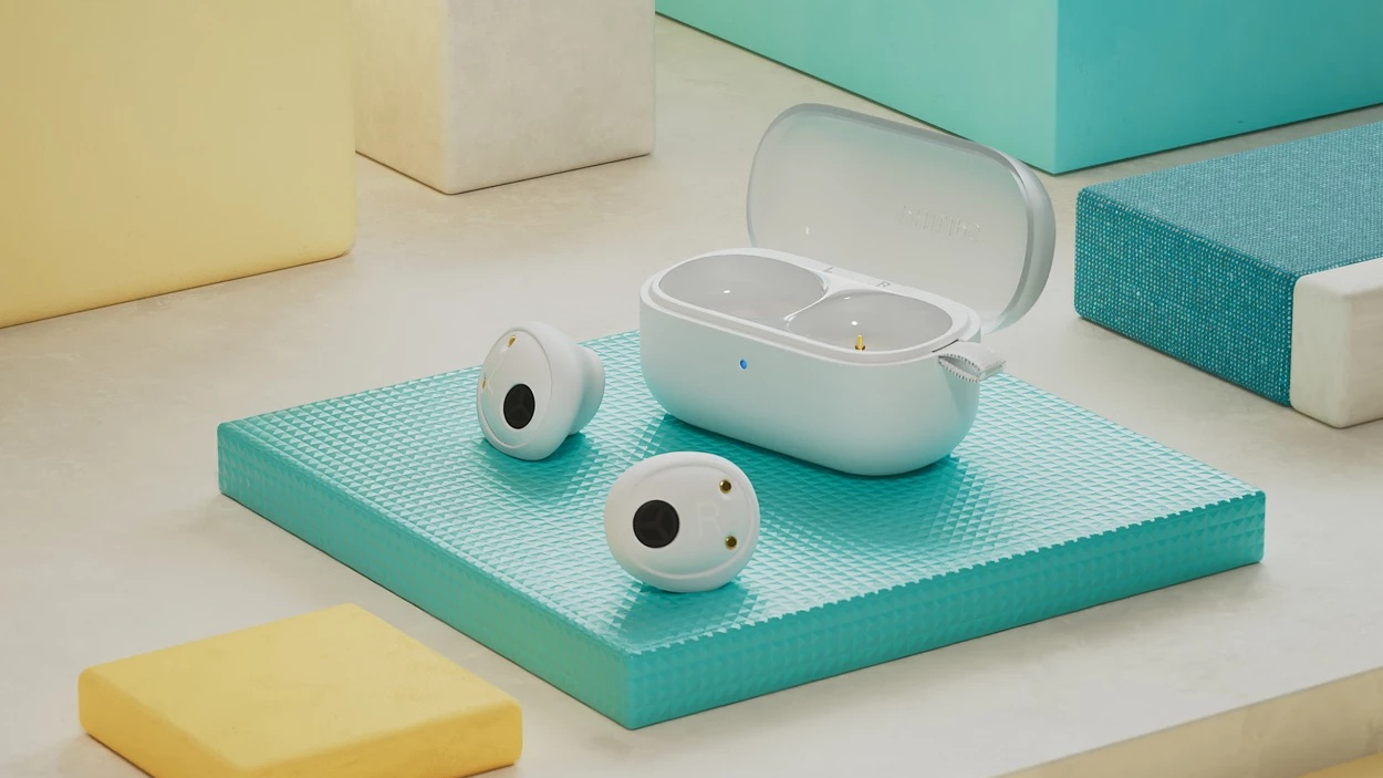 Białe słuchawki, etui i geometryczne bloki na teksturowanej turkusowej powierzchni. Otwarty futerał odsłania przegródki. Żółte i białe bloki w tle.