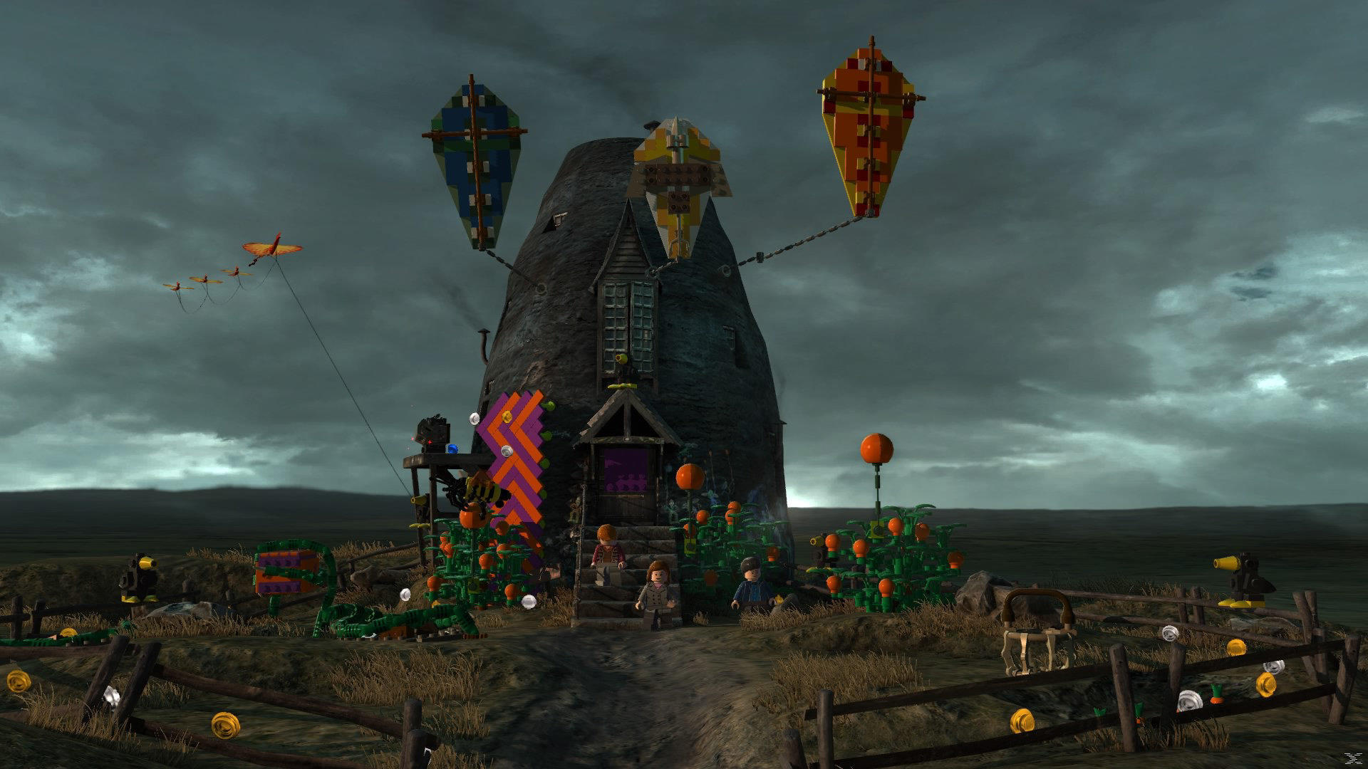 Scena z klocków Lego z wiatrakiem, balonami i uprawami. Trzy postacie stoją na schodach prowadzących do drzwi. Latawiec leci po niebie.
