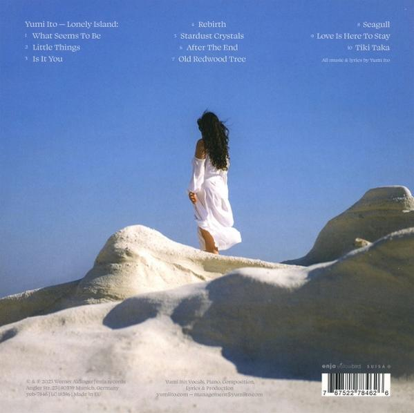 Eine Frau in weißem Kleid steht auf einer weißen Felsformation. Blauer Himmel im Hintergrund. Albumcover.