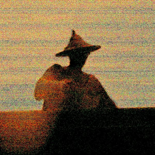 Eine Person mit Hut im Silhouette vor Sonnenuntergang. Die Figur ist dunkel vor dem farbenfrohen Himmel.