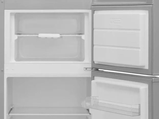 Otwarta lodówka z pustymi przegródkami. Górna część ma szufladę. Dolna część ma półki i półkę na drzwiach.