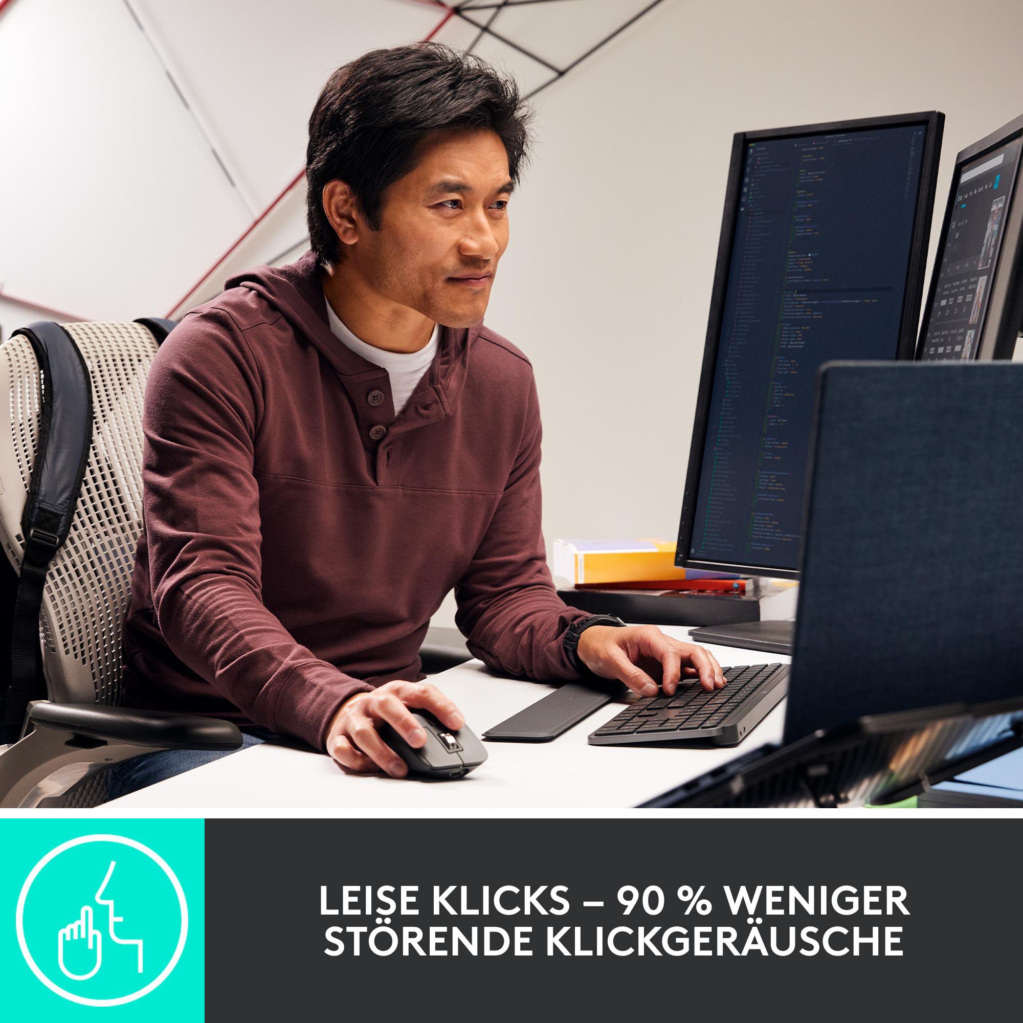 Ein Mann benutzt einen Computer mit zwei Monitoren. Er trägt einen weinroten Kapuzenpullover. Maus und Tastatur liegen auf dem Tisch. Der Hintergrund ist weiß.