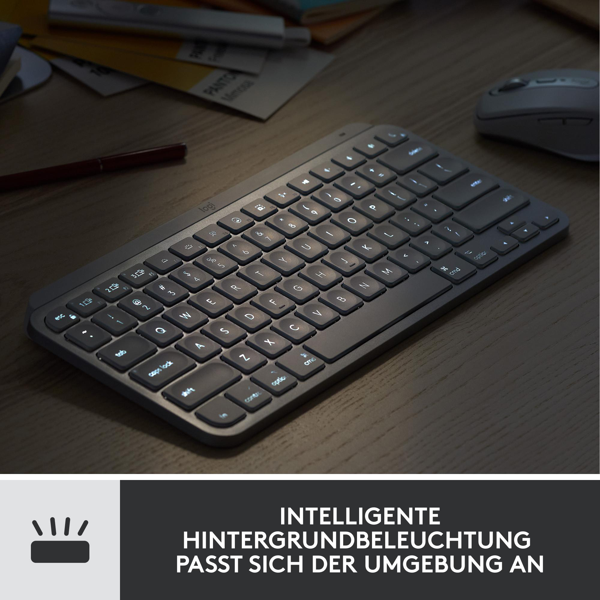 Eine beleuchtete Tastatur auf einem Holztisch. Eine Maus und Papiere befinden sich im Hintergrund. Die Tastatur leuchtet.
