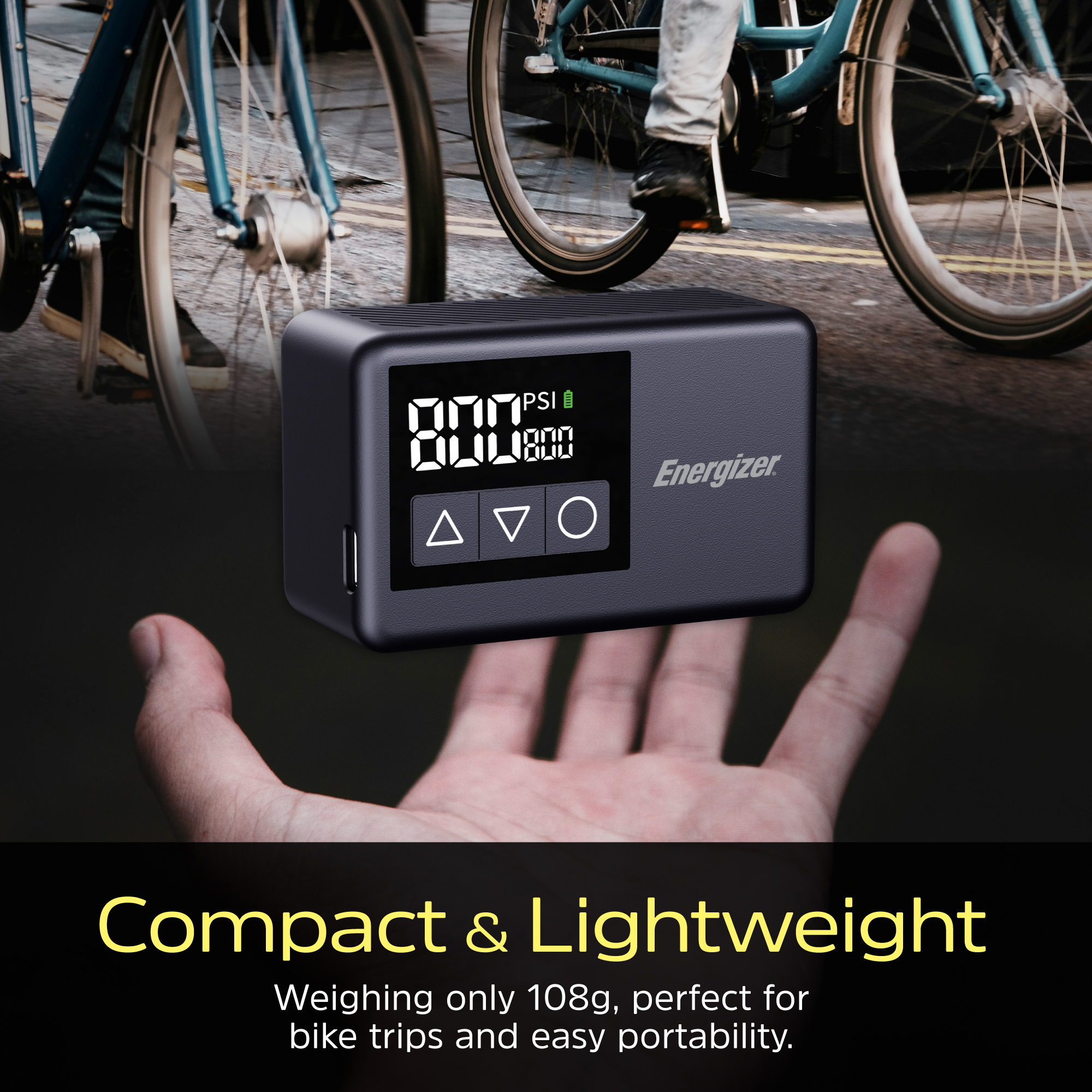 Una mano tiene un gonfiatore digitale per pneumatici accanto alle ruote della bicicletta. Il display mostra PSI e ha pulsanti.