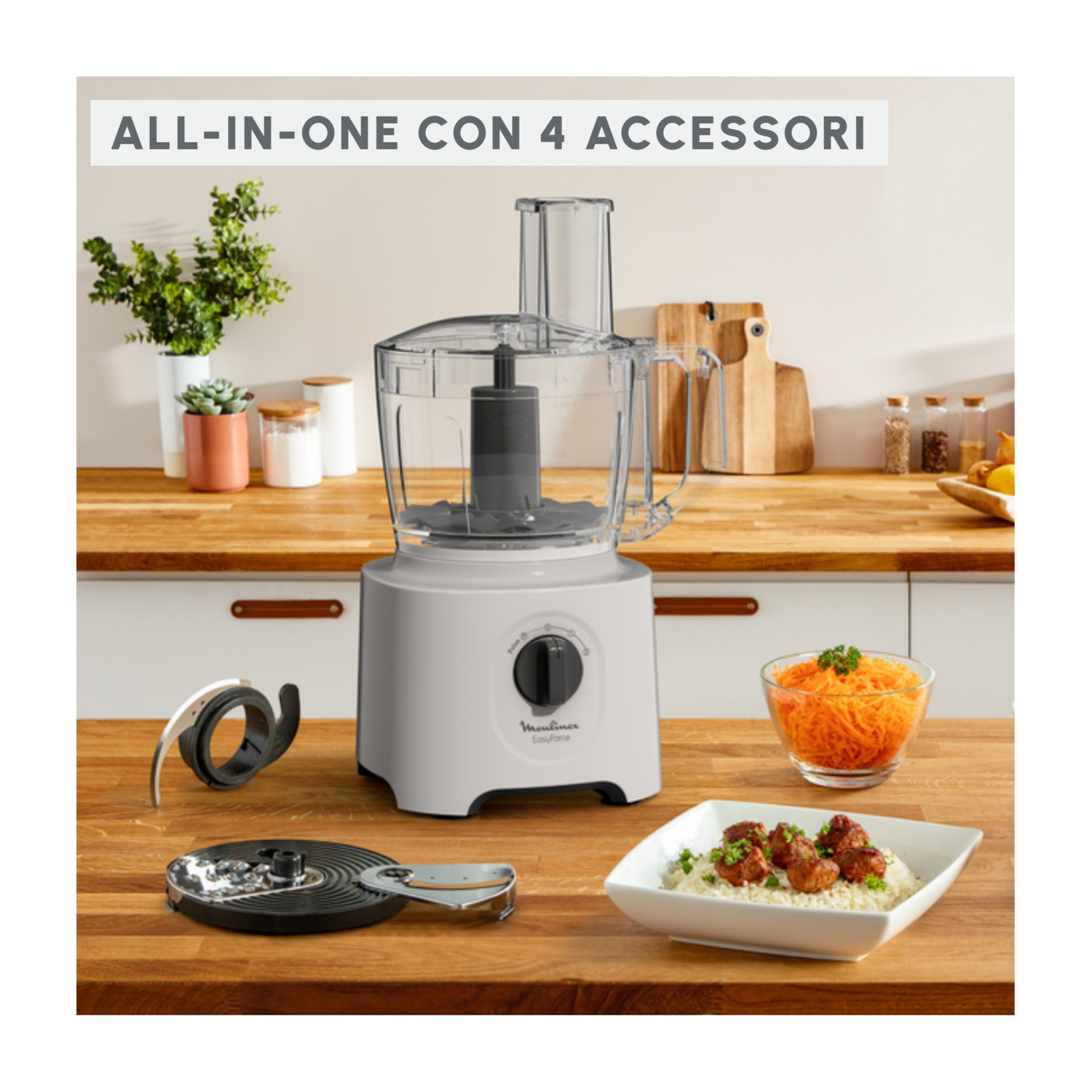 Un robot da cucina con 4 accessori, una ciotola di carote grattugiate e una ciotola di polpette con riso su un bancone di legno.