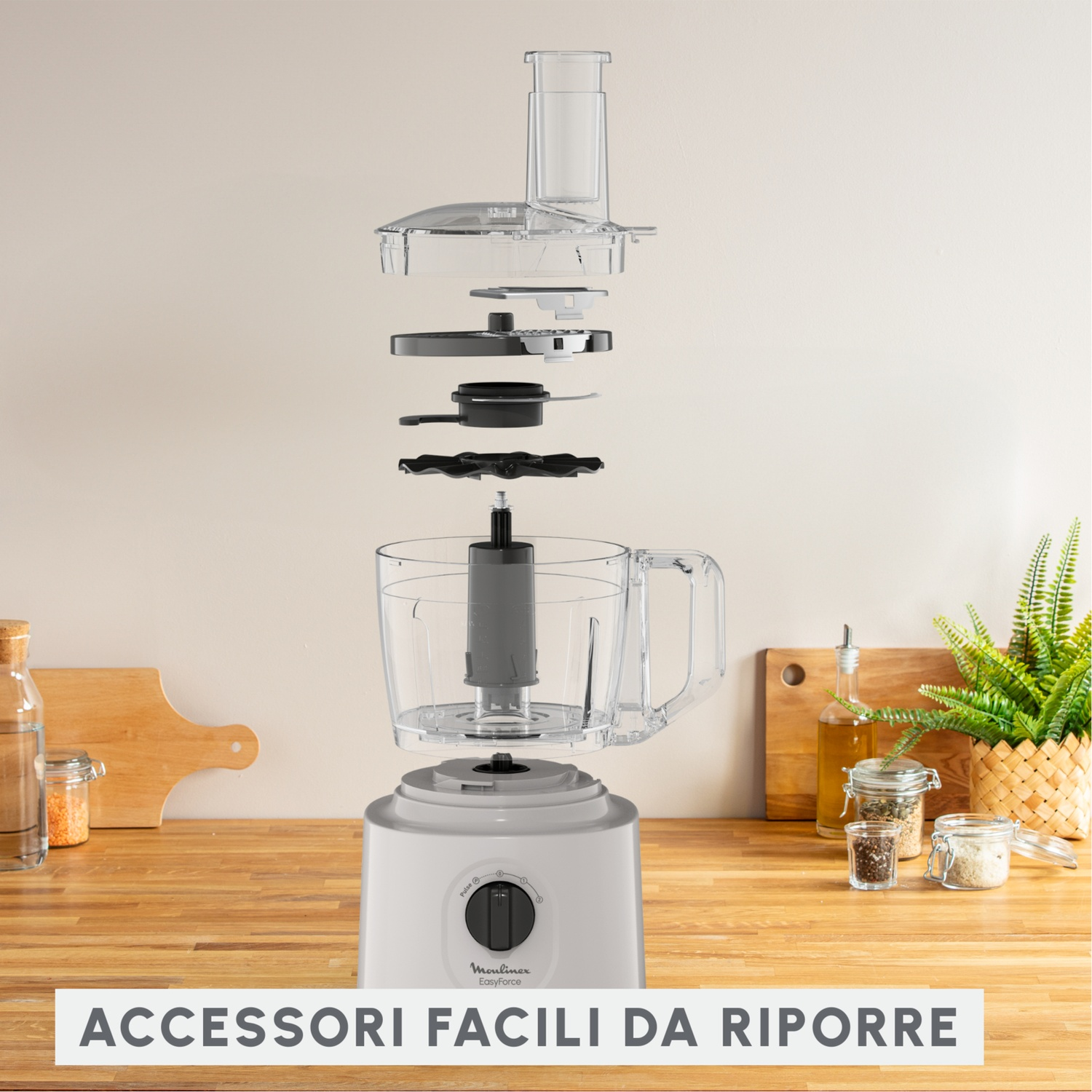 Vista esplosa di un robot da cucina con componenti, su un piano di lavoro in legno. Barattoli e una pianta sullo sfondo. Testo: ACCESSORI FACILI DA RIPORRE.