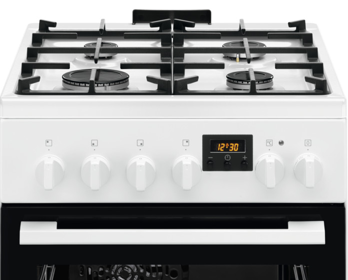 Biała kuchenka gazowa z czarnymi rusztami i palnikami. Ma pokrętła i drzwiczki piekarnika. Zegar pokazuje 12:30.