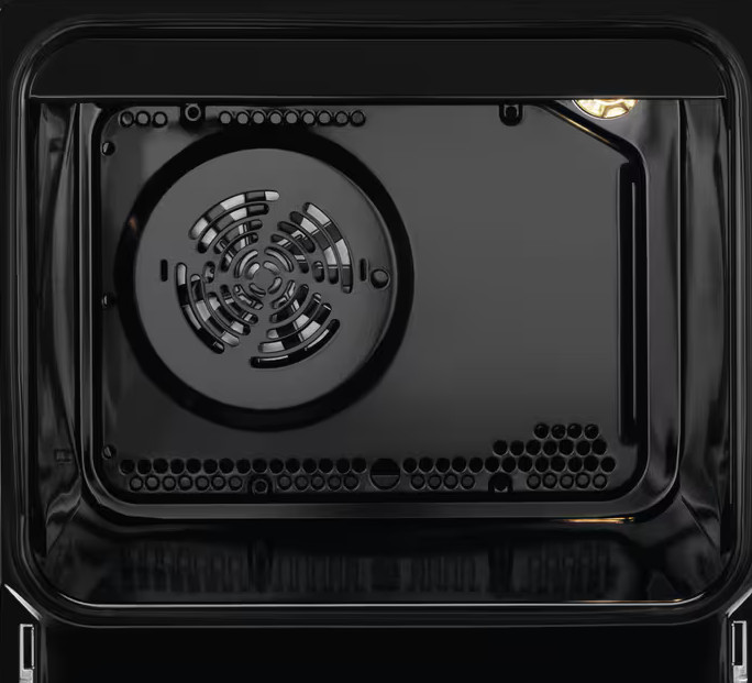 Wnętrze czarnego piekarnika. Wentylator jest na środku, otoczony ciemnym wnętrzem. Światło jest po prawej stronie u góry.