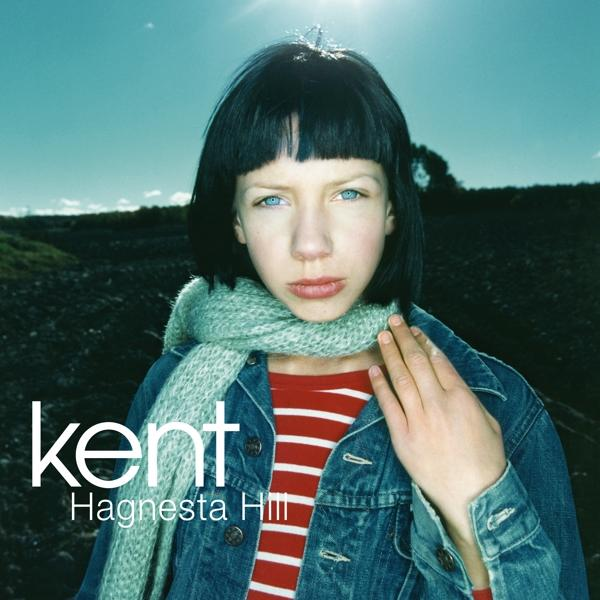 Eine junge Person mit schwarzen Haaren und blauen Augen, trägt einen Schal und eine Jeansjacke. Text links: 'kent' und 'Hagnesta Hill'.