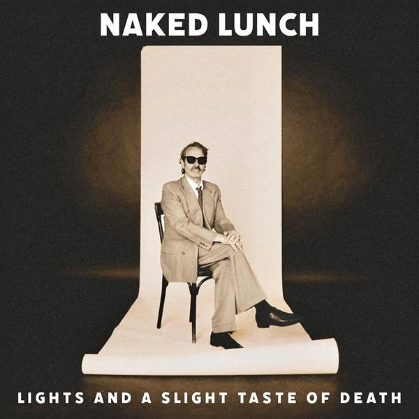 Ein Mann im Anzug sitzt vor einem weißen Hintergrund auf einem Stuhl. Die Worte 'Naked Lunch' und 'Lights and a Slight Taste of Death' sind sichtbar.