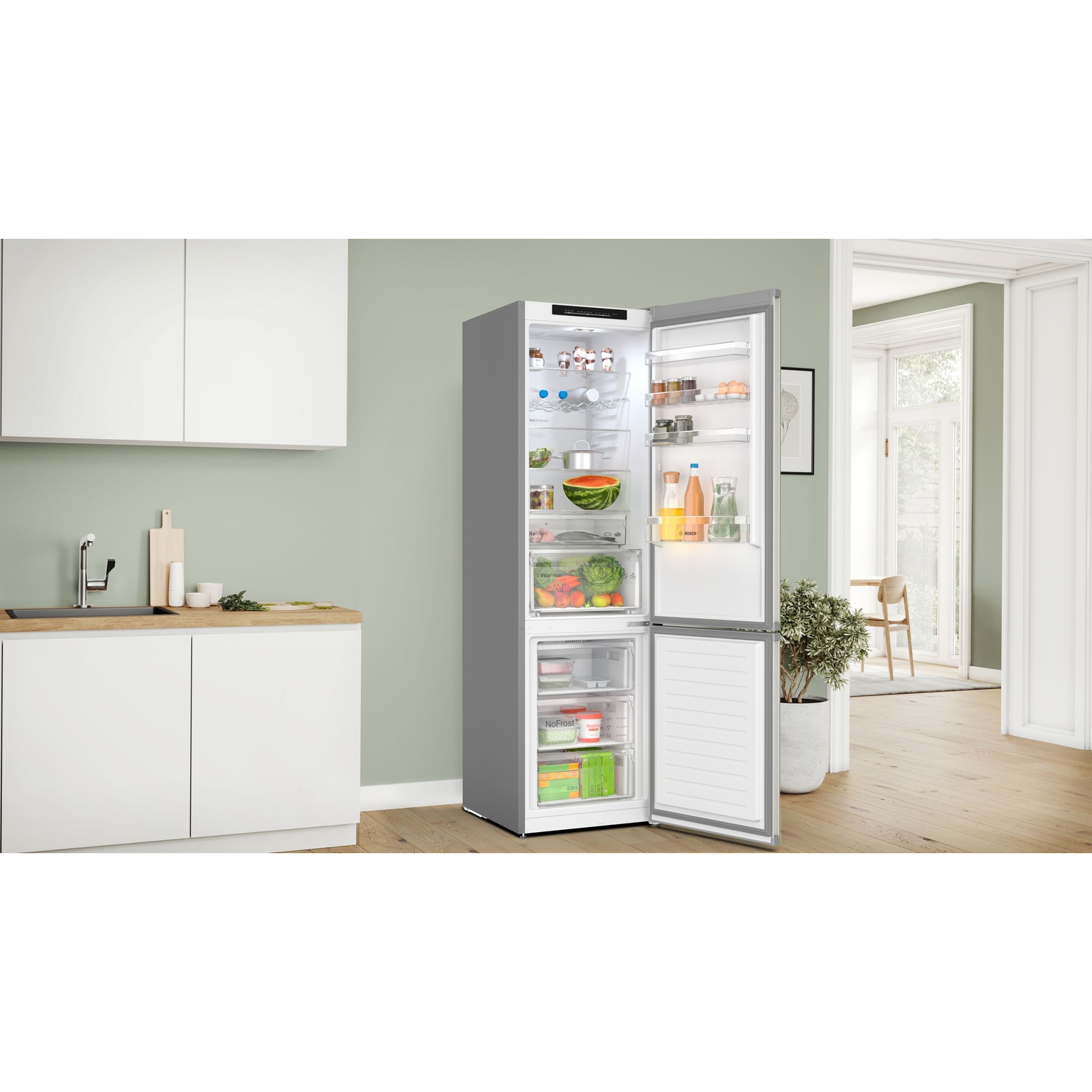 Un frigorifero moderno e aperto pieno di cibo. È in un ambiente cucina con un bancone. Lo sfondo comprende una zona pranzo.