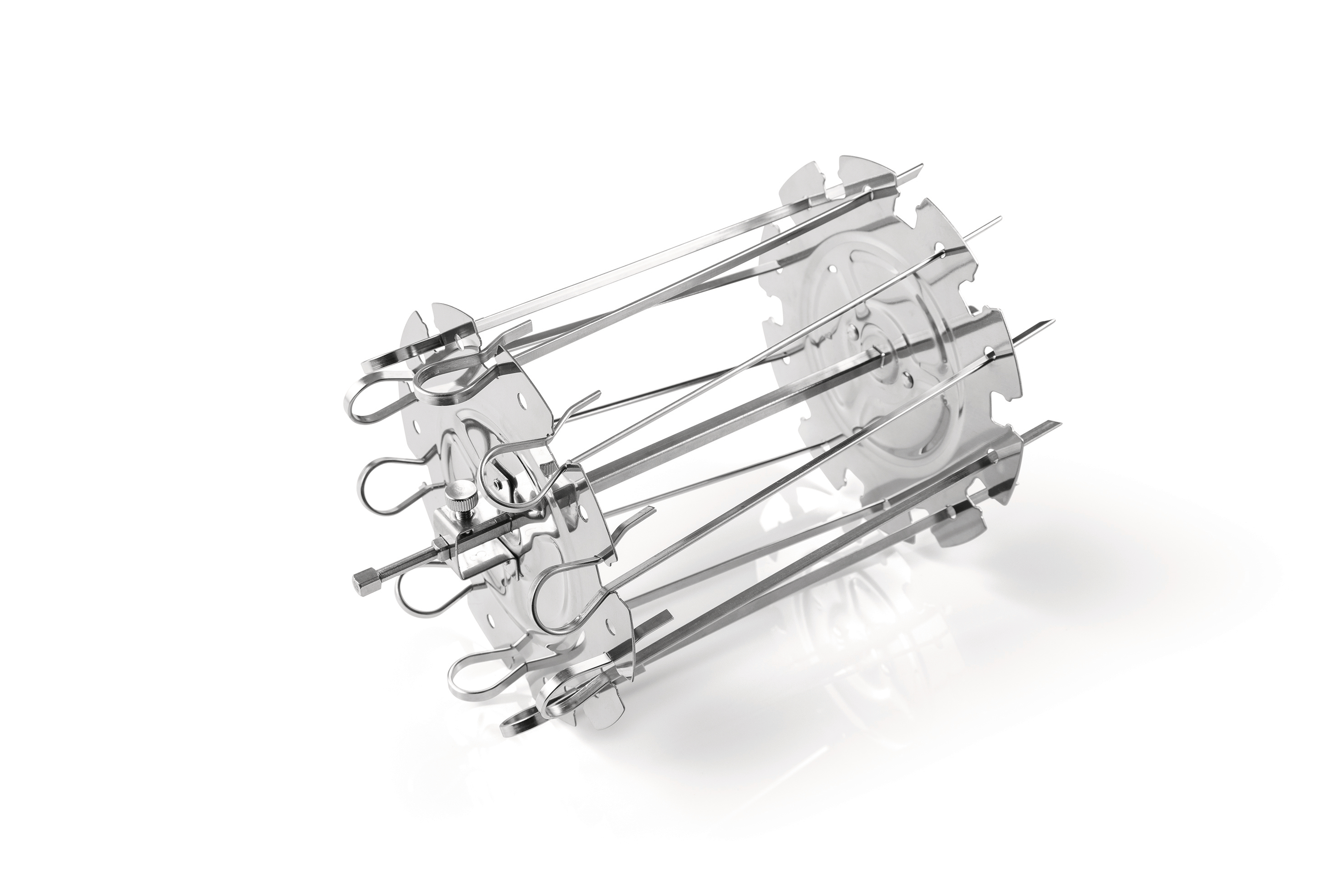 Ein Edelstahl-Rotisserie-Aufsatz. Er hat ein kreisförmiges Design mit nach außen ragenden Spießen, auf weißem Hintergrund.