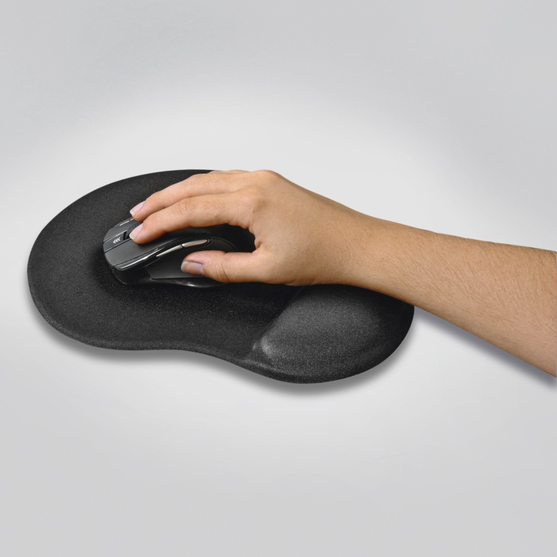 Une main utilise une souris d'ordinateur noire sur un tapis de souris noir avec support de poignet, sur une surface blanche.