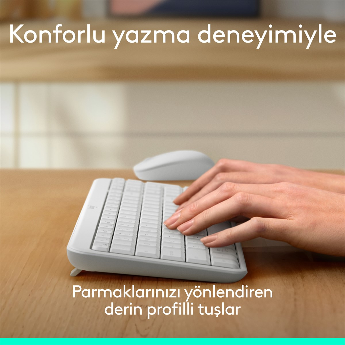 Eller beyaz bir klavyede yazıyor. Arka planda beyaz bir fare var. Klavye ahşap bir yüzeyde duruyor.