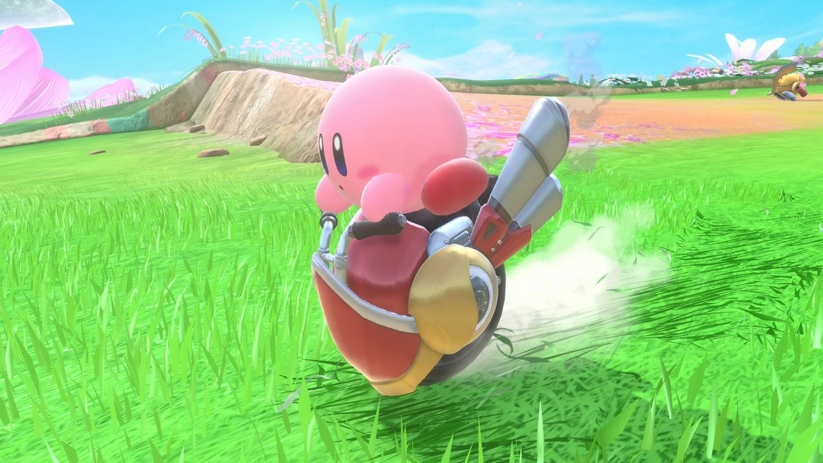 Pink Kirby on a vehicle flies over a green field. The vehicle has a red and yellow design with smoke trails.