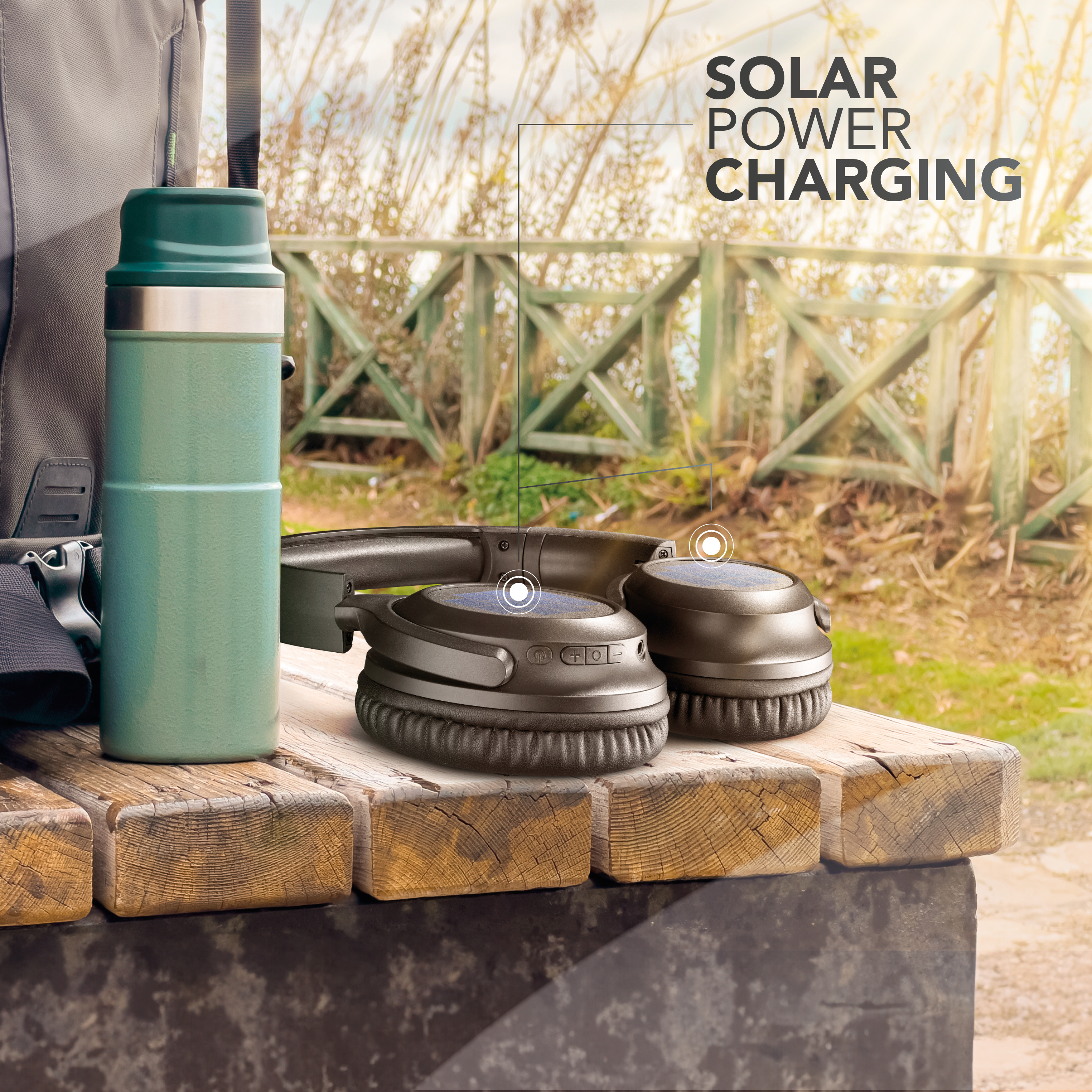 Casque avec charge solaire sur un banc en bois, à côté d'une thermos et d'un sac à dos. L'arrière-plan montre une clôture et du soleil.
