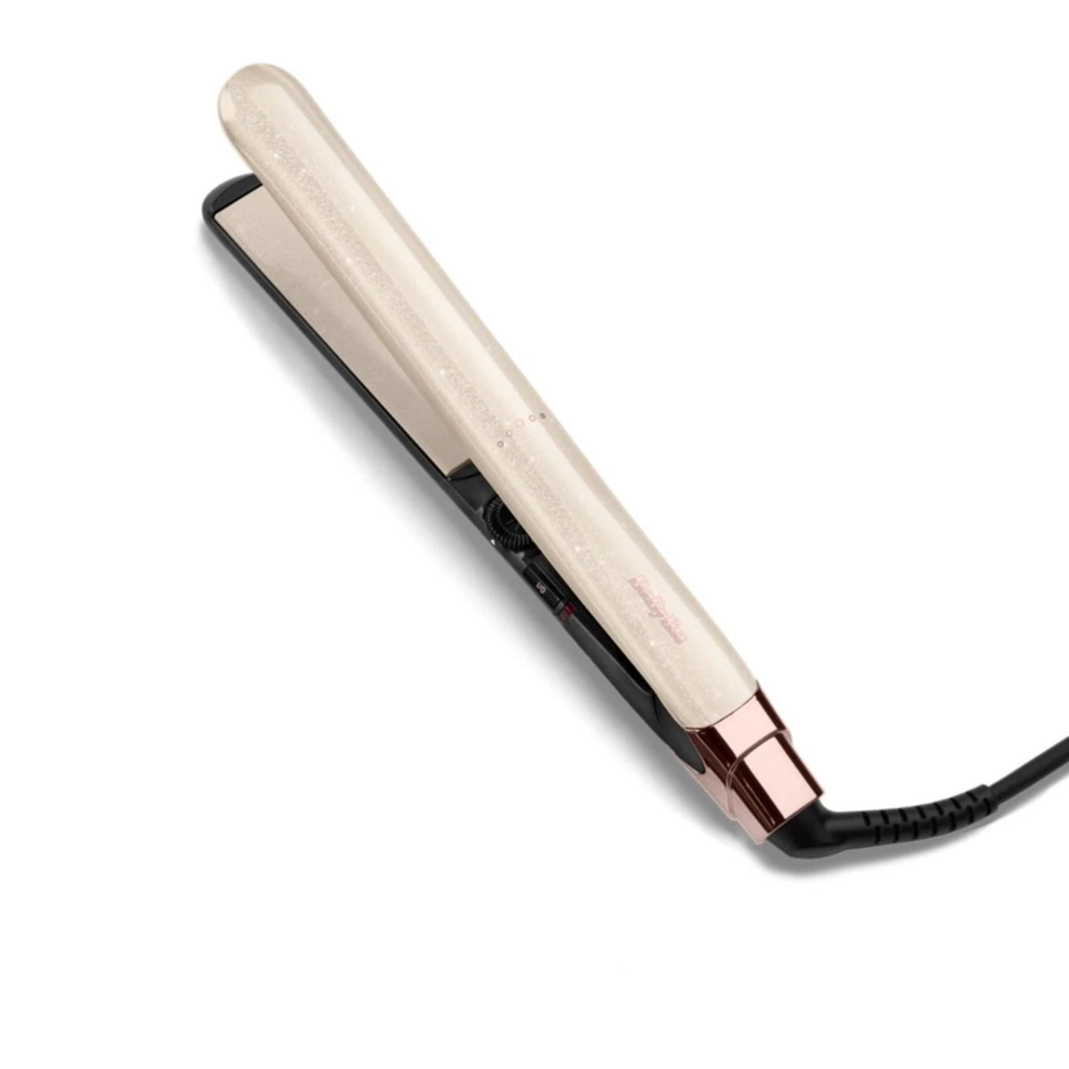 A flat iron, mostly cream-colored with a black base, lies on a white surface. It has a rose-gold accent and a black power cord.