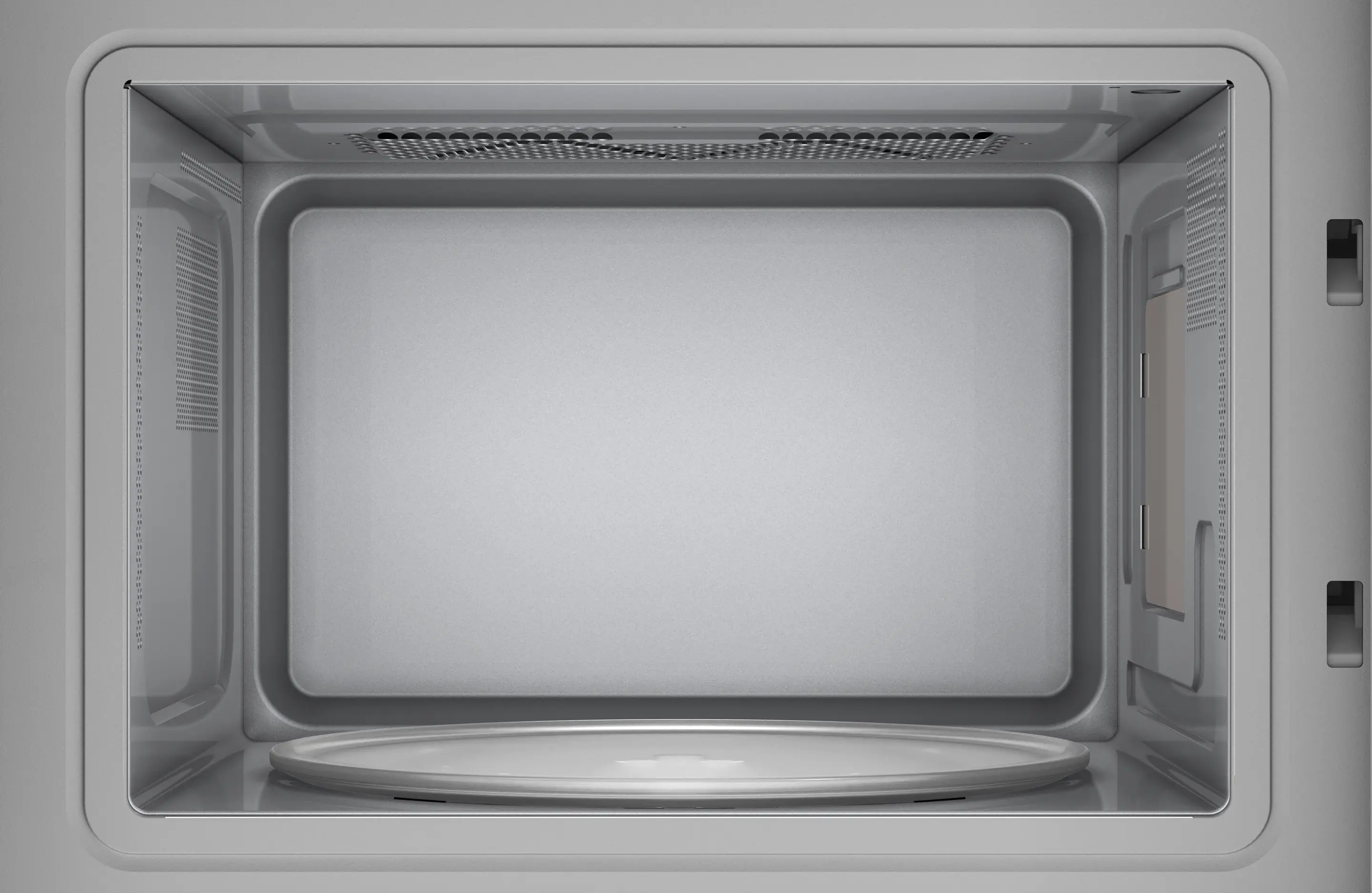 Dentro de un microondas, una placa de vidrio en la base. El interior es gris y tiene ventilas.