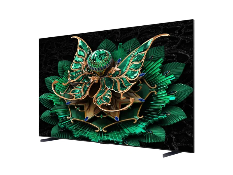 Egy modern TV egy részletes zöld-arany virágot jelenít meg. Fekete textúrájú háttérrel rendelkezik, és fekete lábakra van szerelve.