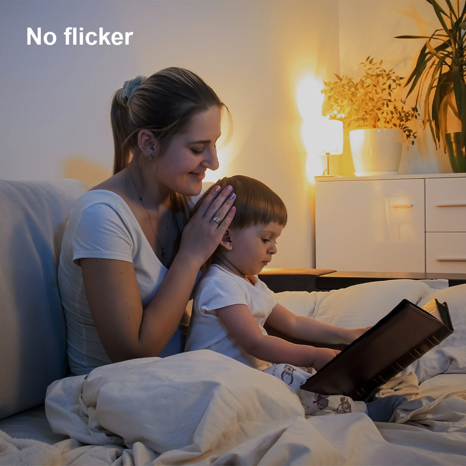 Een vrouw en een kind zitten op bed. De vrouw raakt het haar van het kind aan, terwijl het kind naar een boek kijkt.