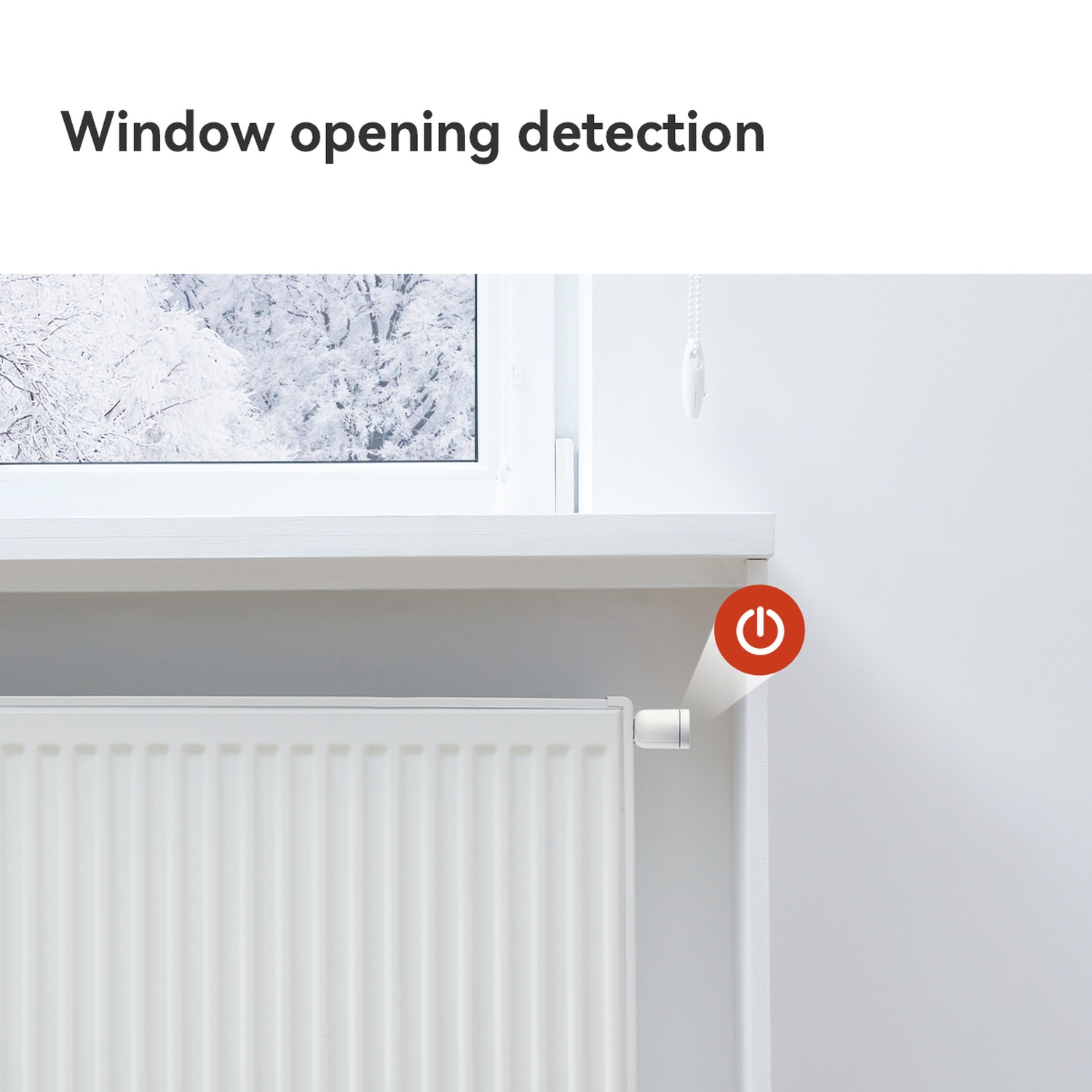 Een witte radiator bevindt zich onder een raam met een besneeuwd uitzicht. Een rode aan/uit-knop bevindt zich in de buurt van de radiator.