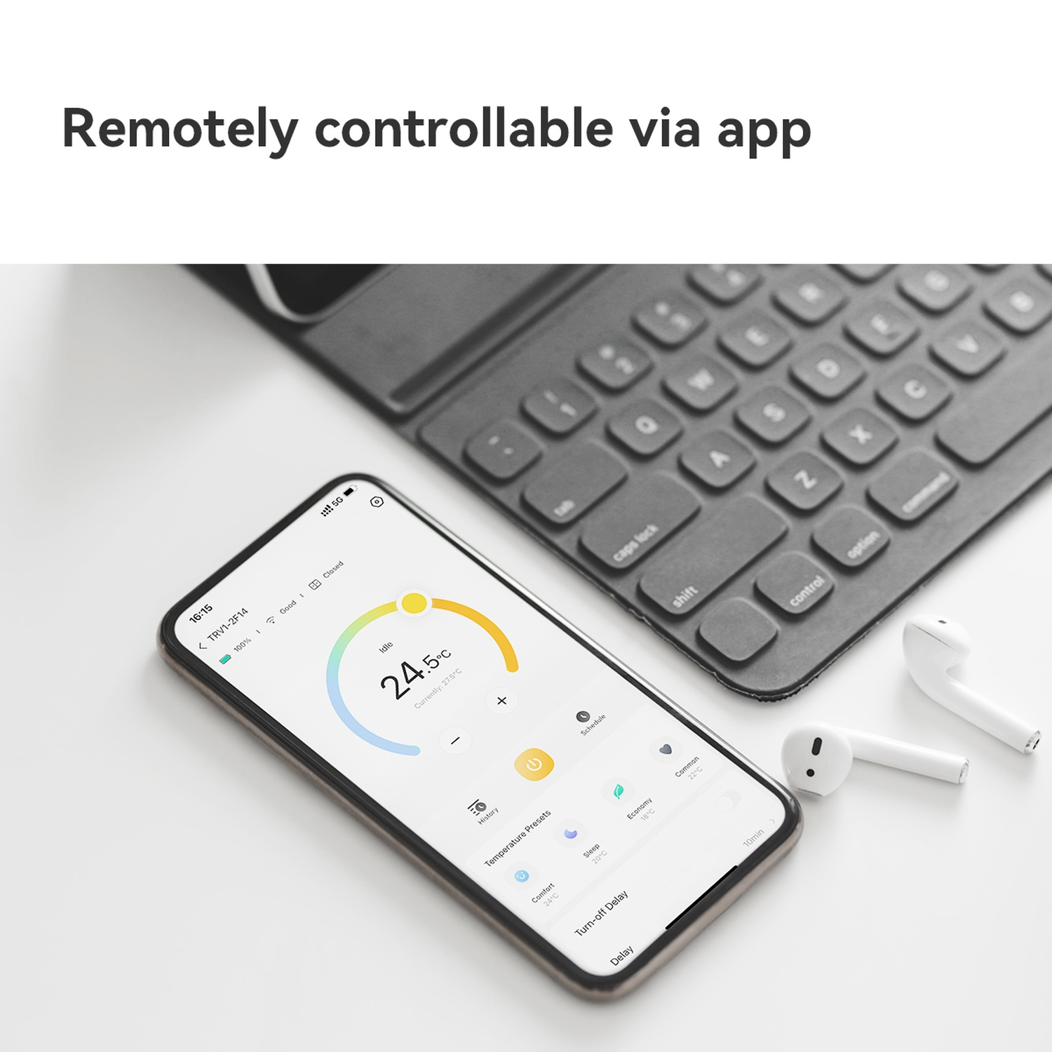 Een smartphone toont een temperatuurregelingsapp, in de buurt van een toetsenbord en witte oortelefoontjes. Het scherm toont 24,5°C.